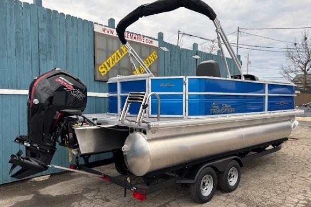 2026 Sun Tracker Party Barge 20 DLX pontoon boat on trailer, blue and silver design.