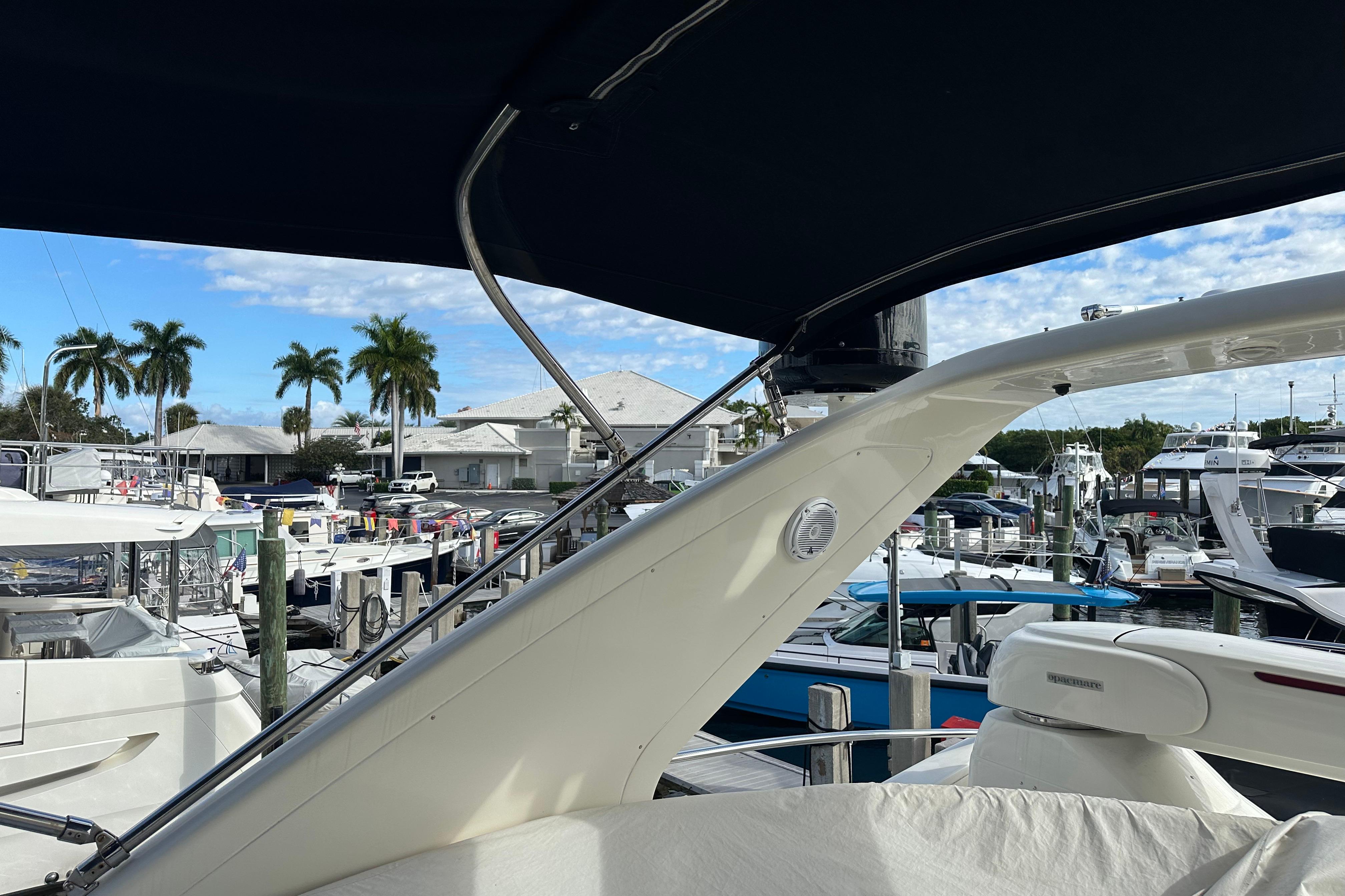 2004 Azimut 55E yacht docked at marina with palm trees and blue sky.