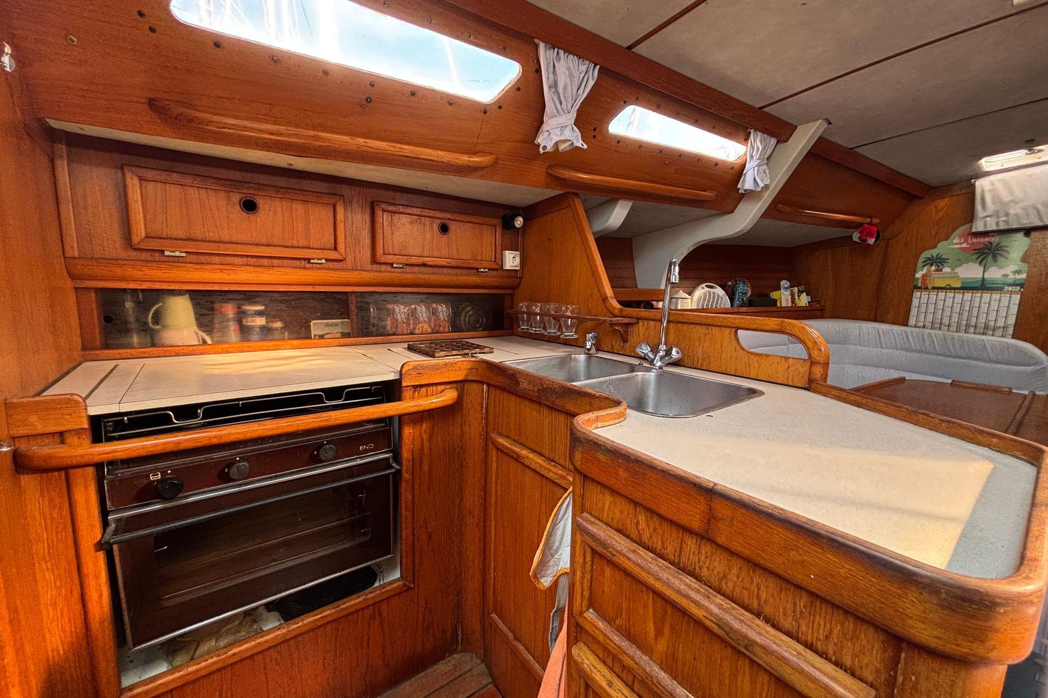 Interior of 1986 Jeanneau Sun Shine 38 sailboat, featuring a wooden kitchen and dining area.