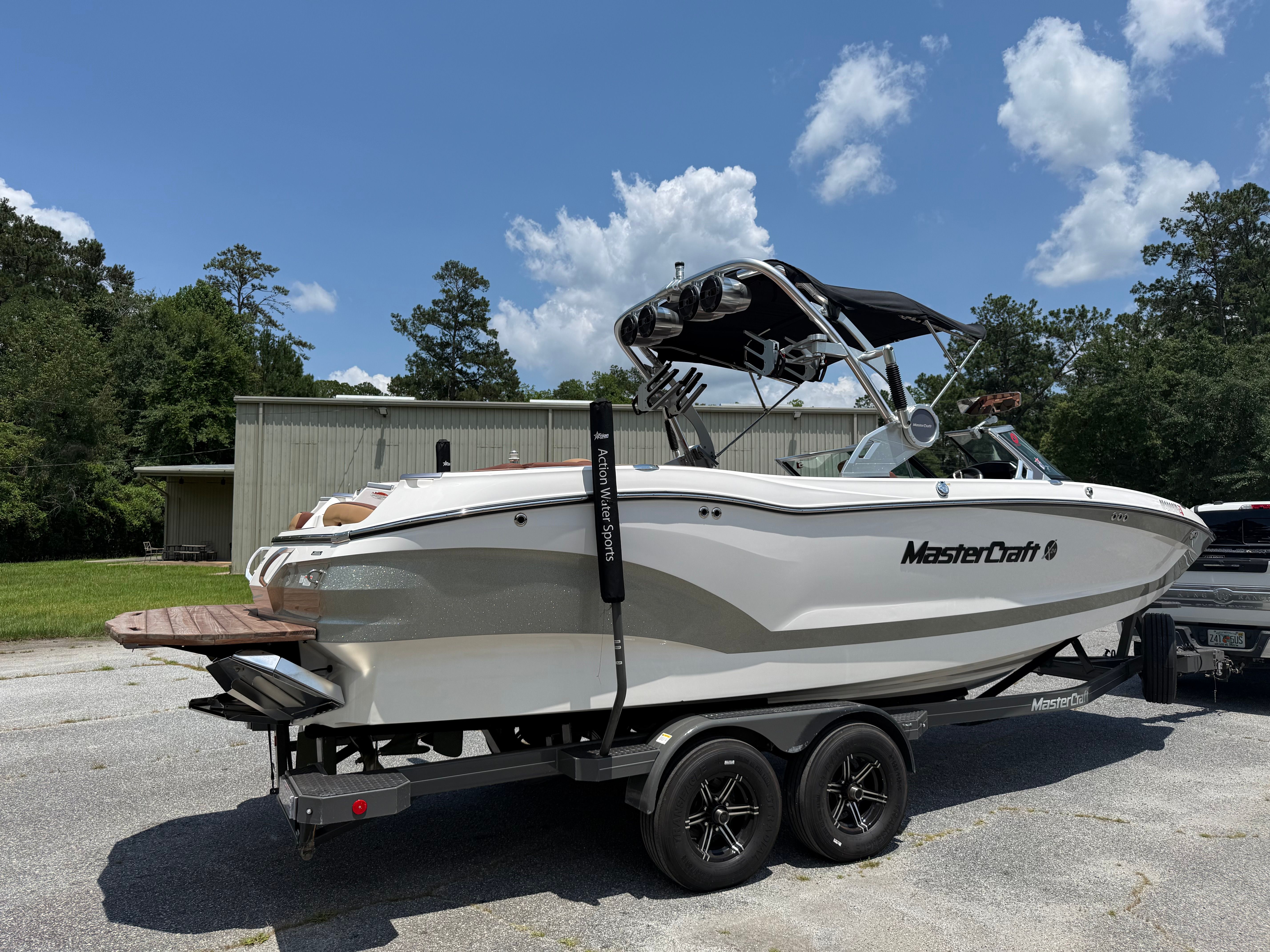 A white 2021 MasterCraft X24 boat on a trailer in a parking area.