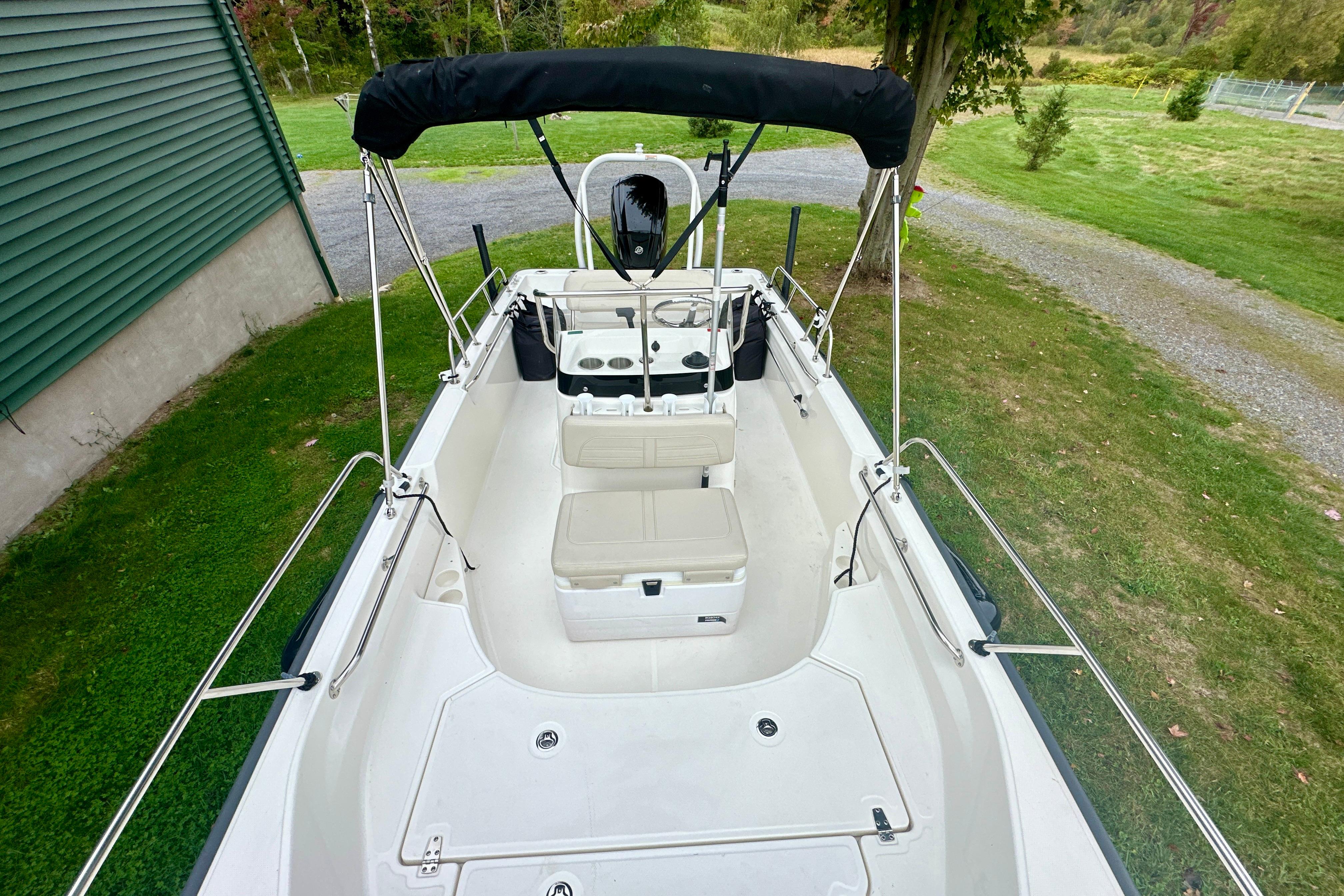 2024 Boston Whaler 170 Montauk boat with seating and canopy, parked on grass.