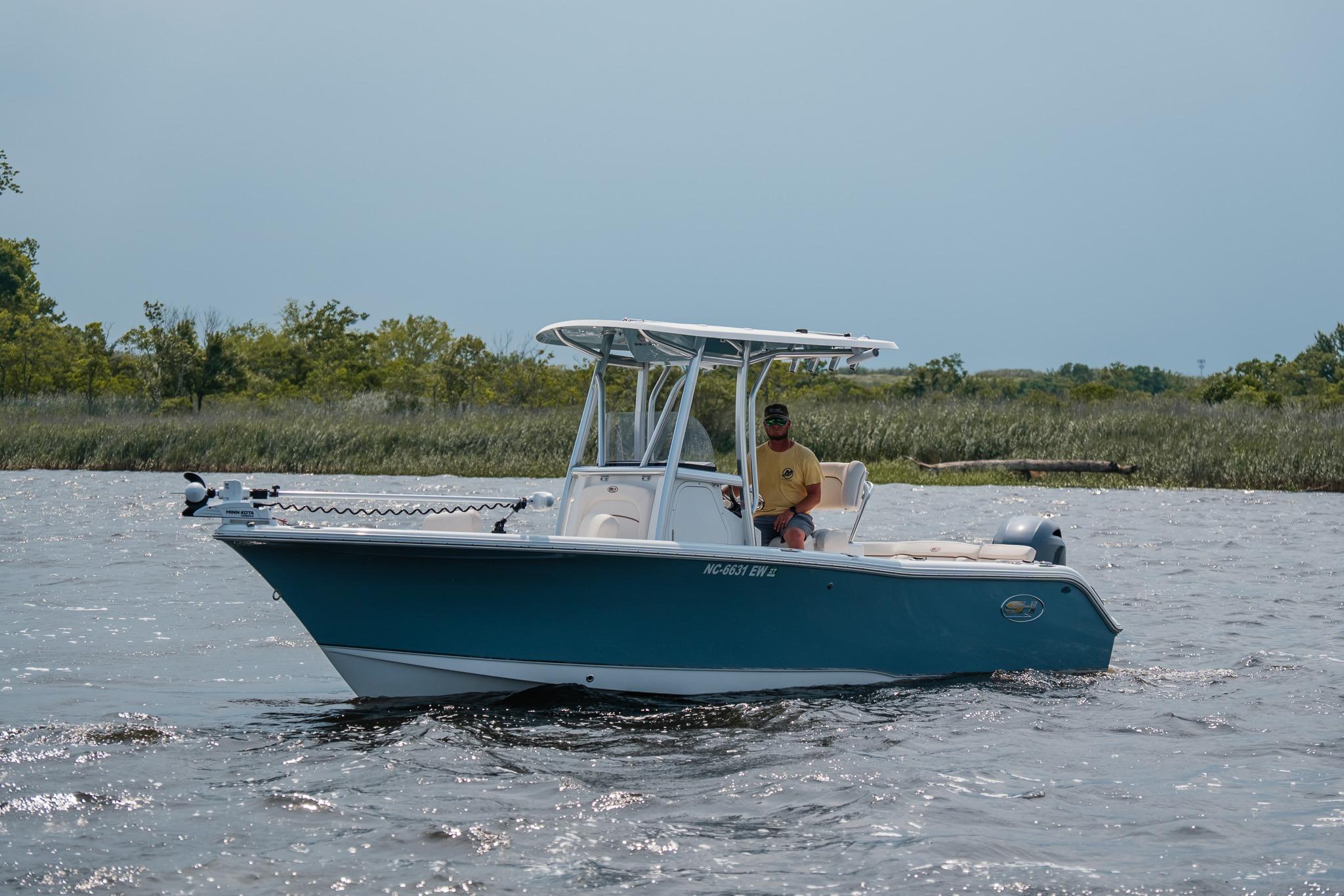 2022 Sea Hunt Ultra 229 boat cruising on a calm river with lush greenery in the background.