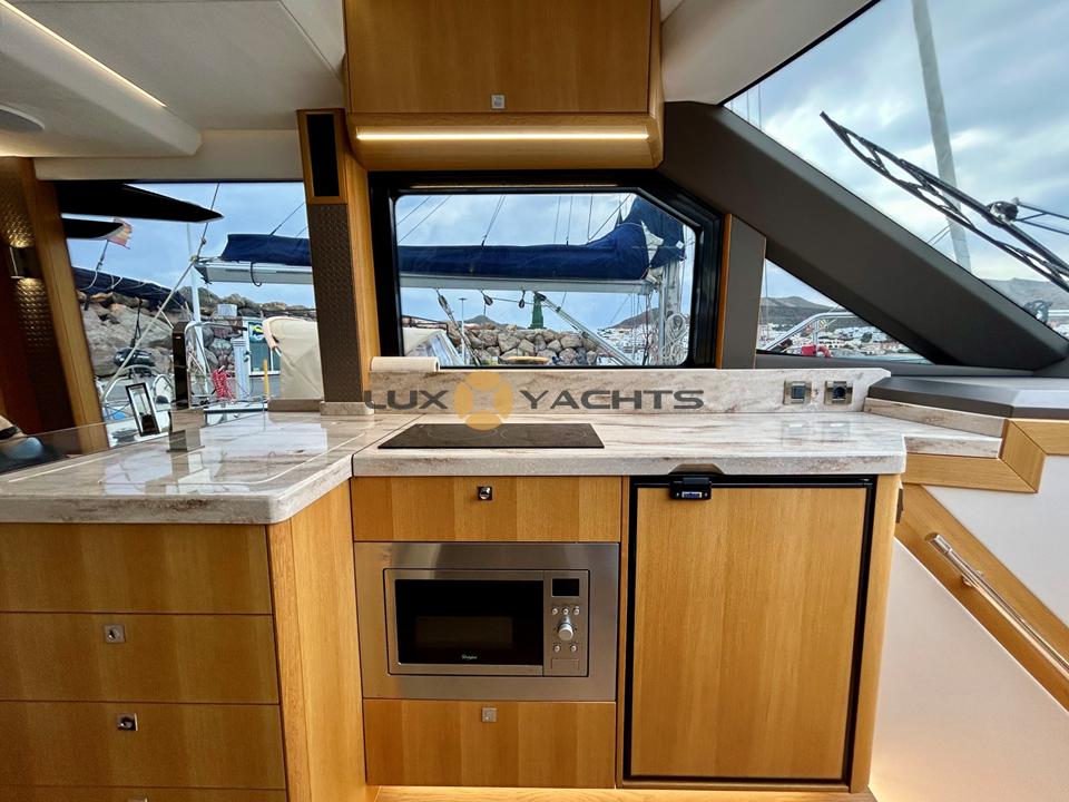 Modern kitchen interior of 2021 Galeon 400 Fly yacht with wood cabinetry and appliances.