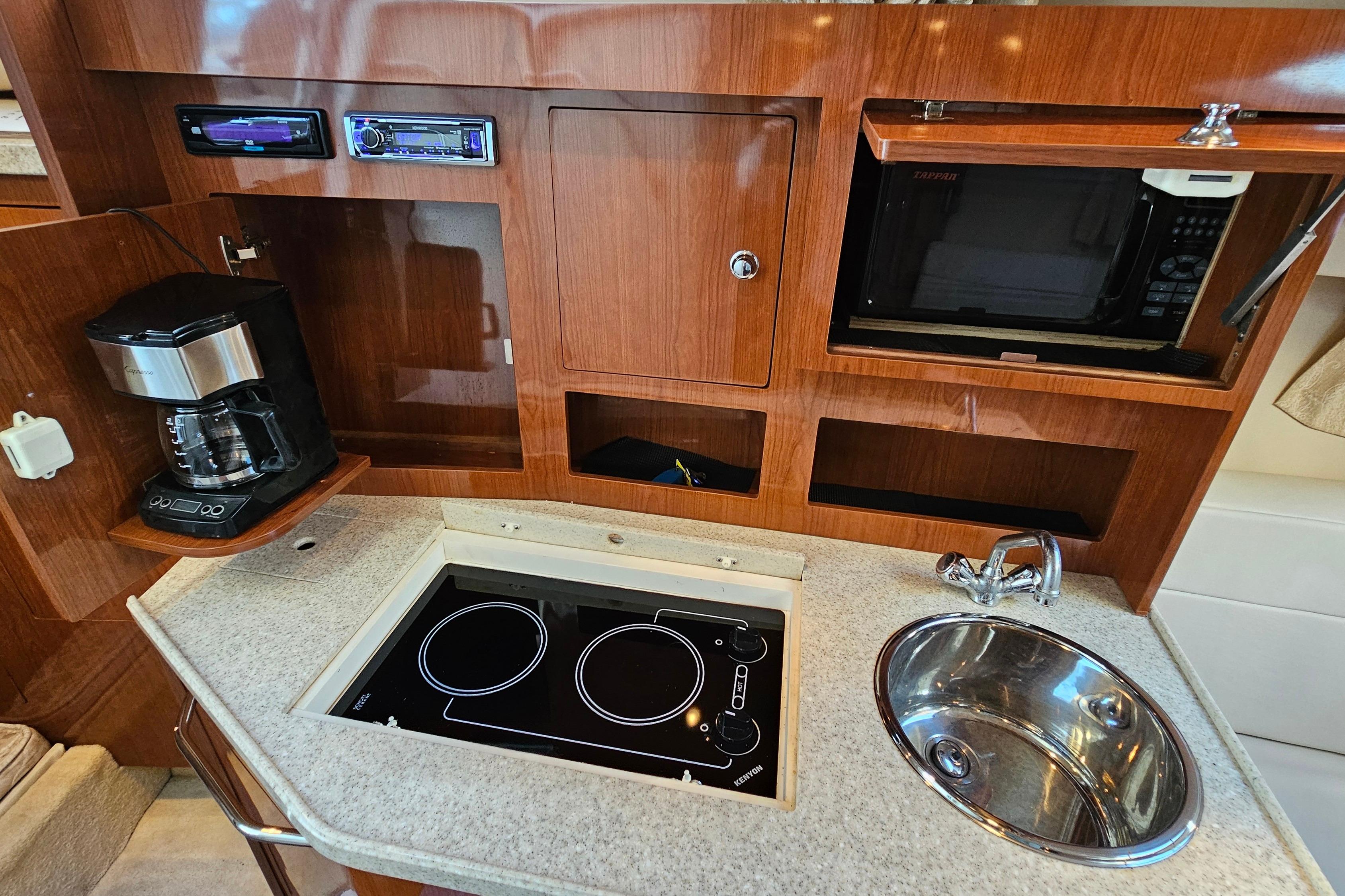 2005 Regal 3060 Window Express yacht kitchen with stove, sink, microwave, and coffee maker.