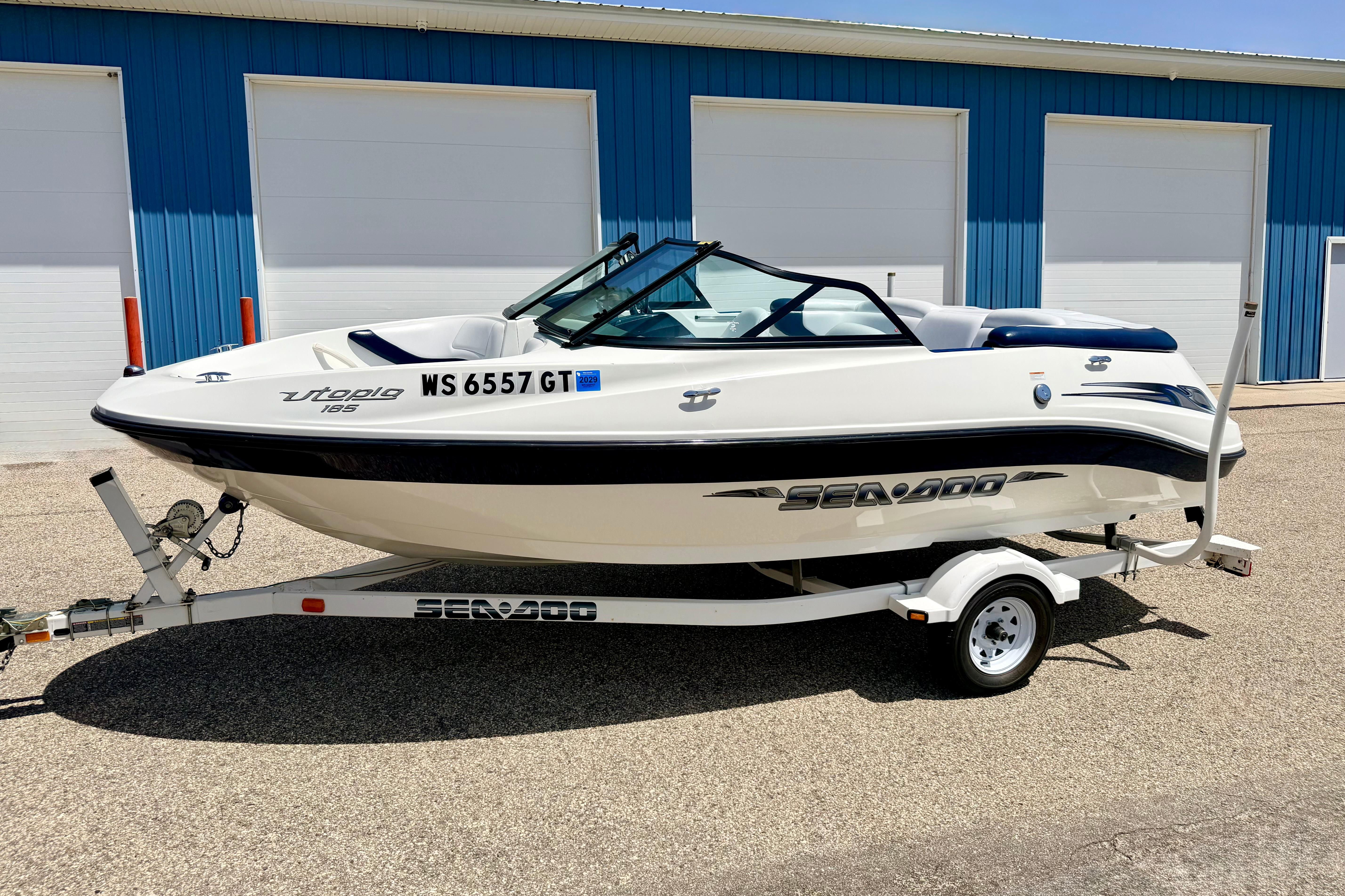 2004 Bombardier SEADOO Utopia 185 boat on trailer, parked outside blue building.