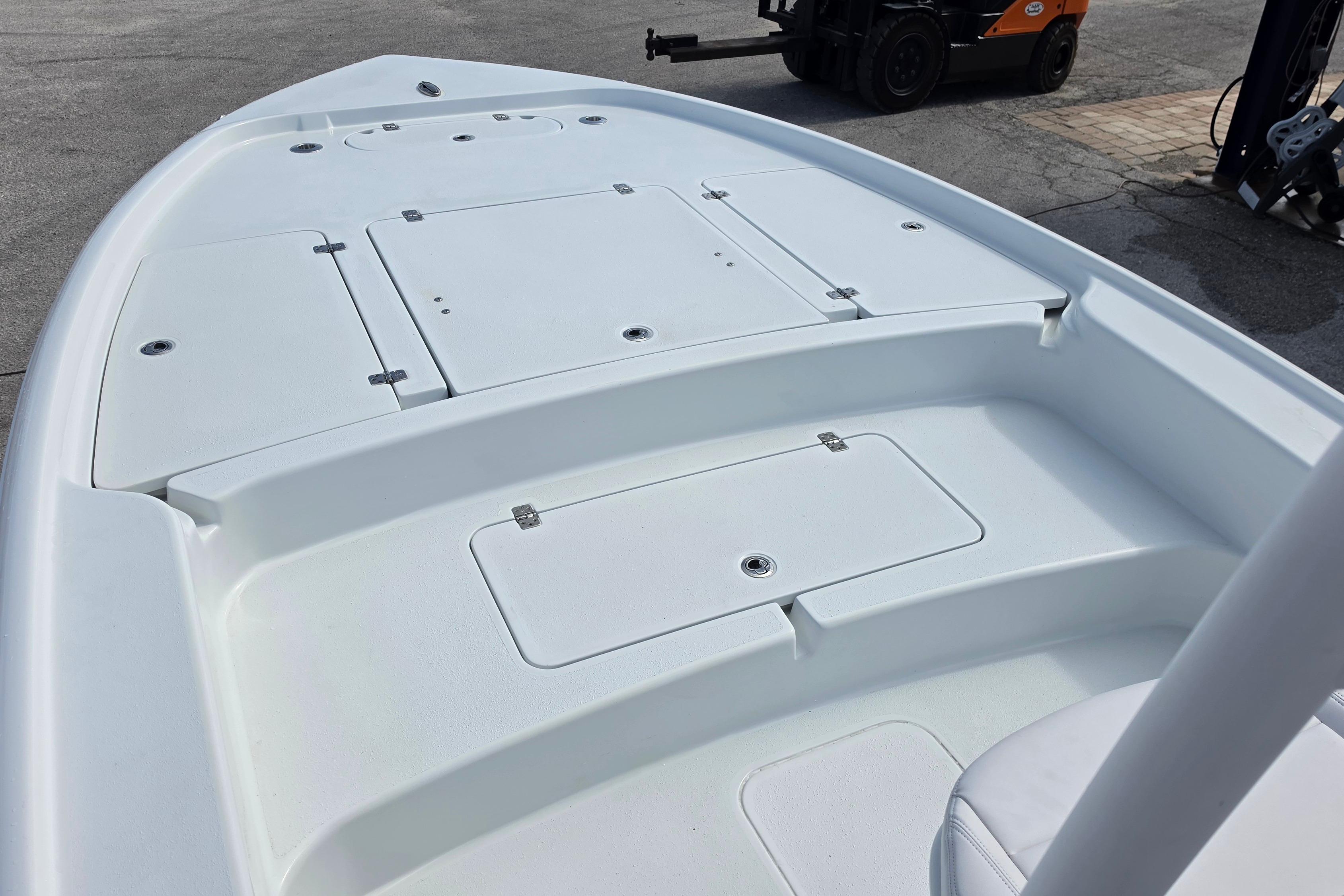 2026 Yellowfin 24 Bay CE boat deck with storage compartments, shown in a marina setting.
