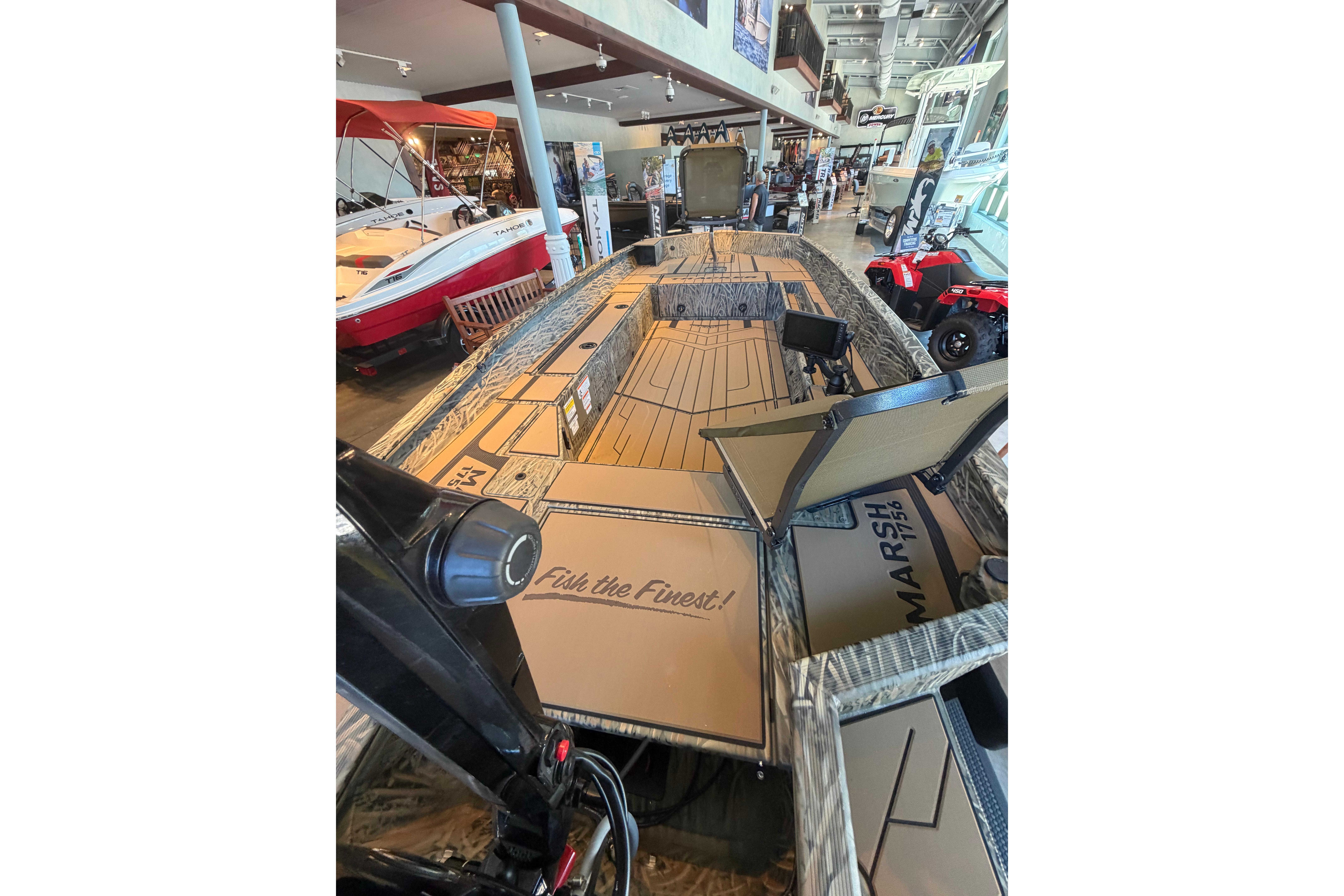 2026 Tracker Grizzly 1756 T Marsh boat displayed in showroom, featuring spacious deck and storage.