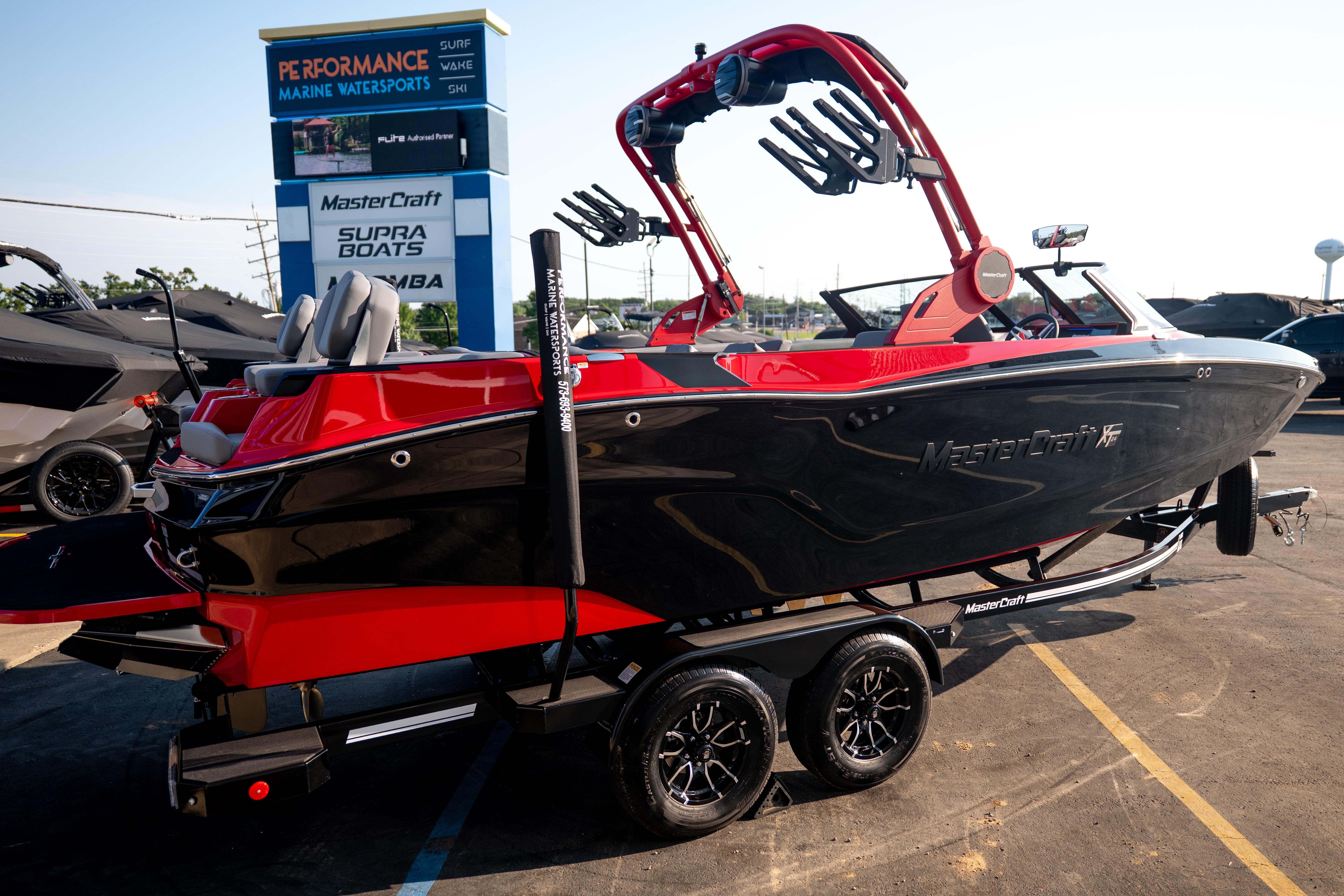 2027 MasterCraft XT24 boat in black and red on a trailer at a dealership.