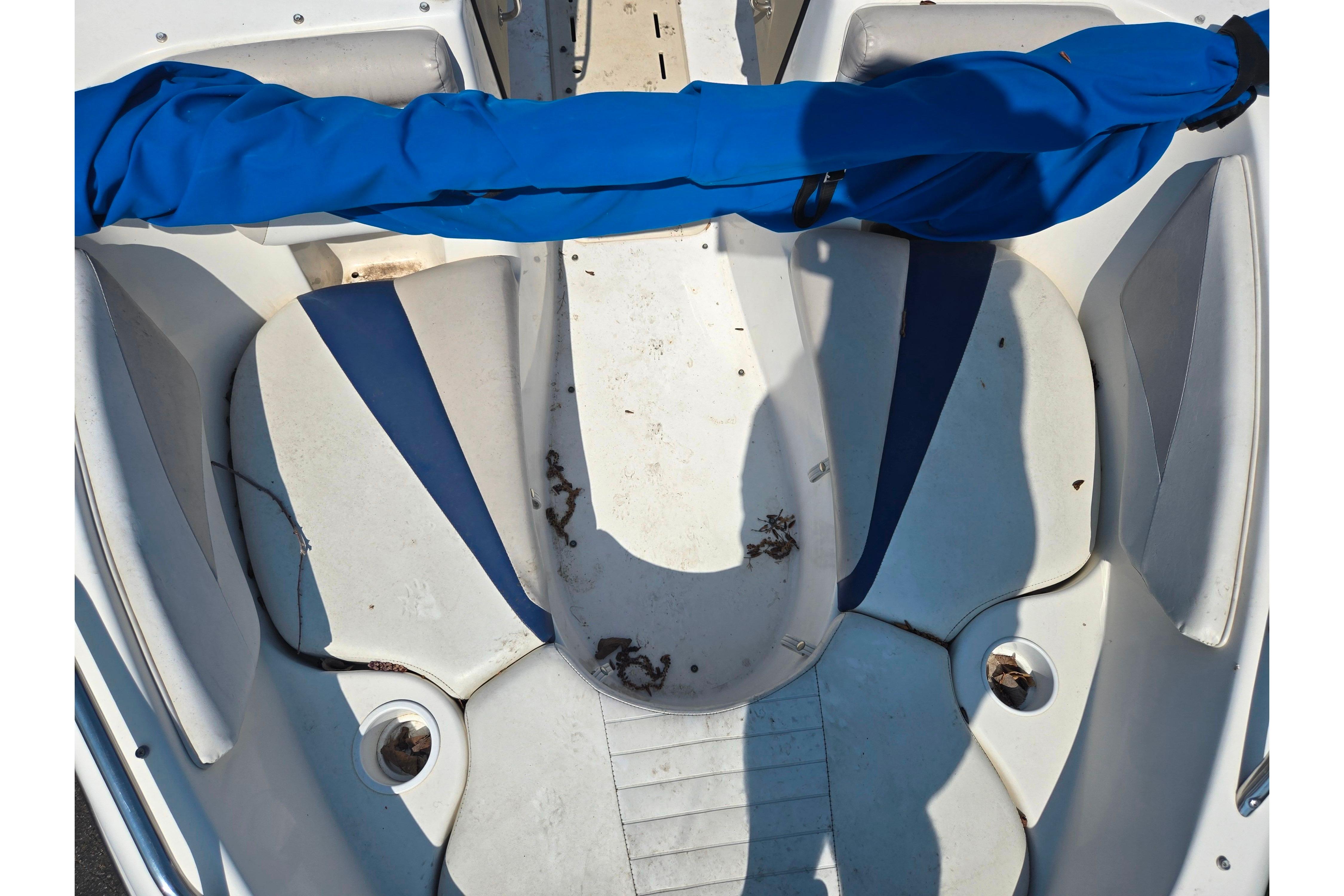 2007 Glastron GT 185 boat interior with blue and white seating, showing some debris.