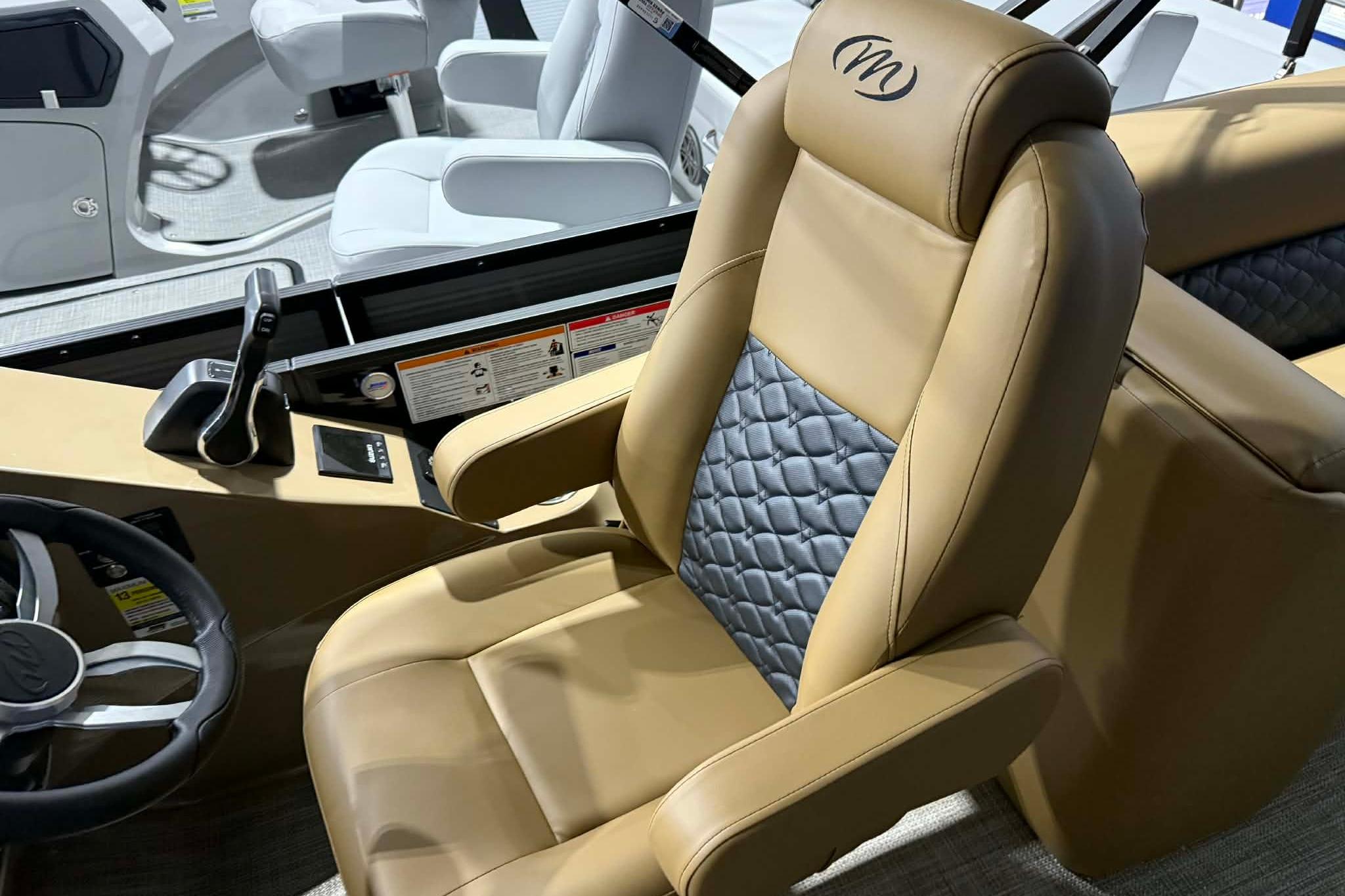 Luxurious captain's chair in 2026 Manitou Encore VP 230 boat, featuring tan and gray upholstery.