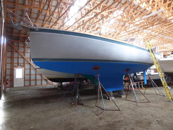 1989 Nonsuch 30 Ultra sailboat in storage, supported by stands, inside a wooden structure.