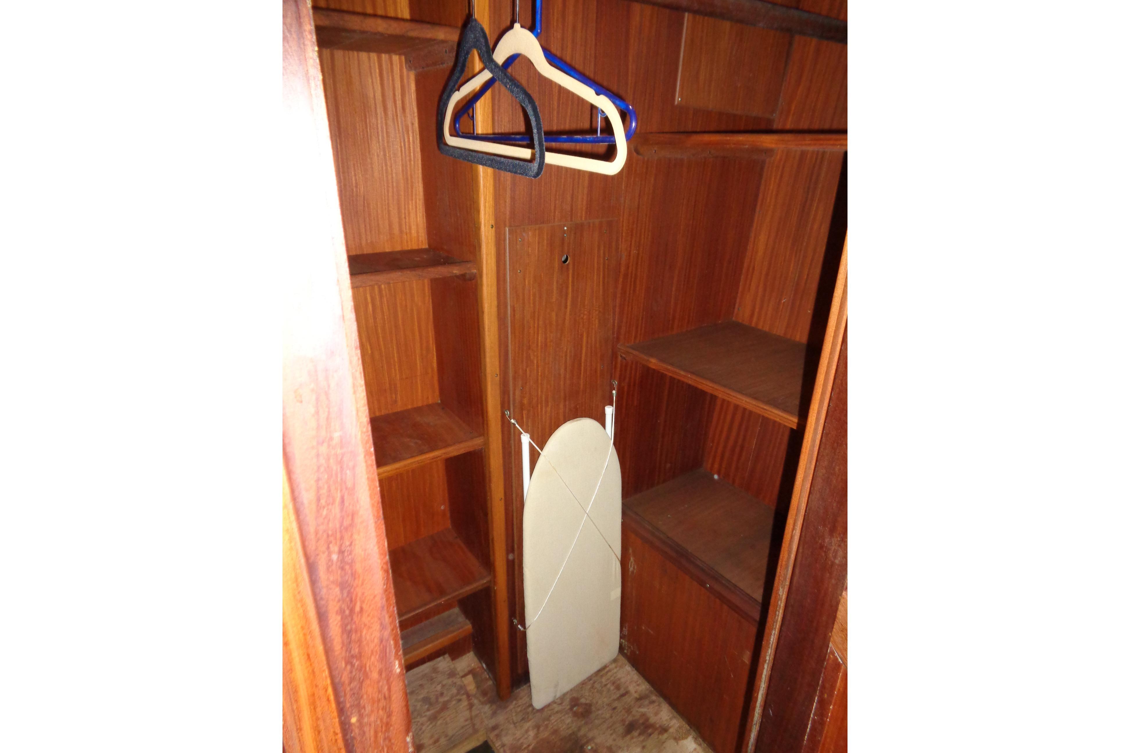 Wooden closet interior on 1981 Hatteras 48 Cockpit Motor Yacht with hangers and shelves.