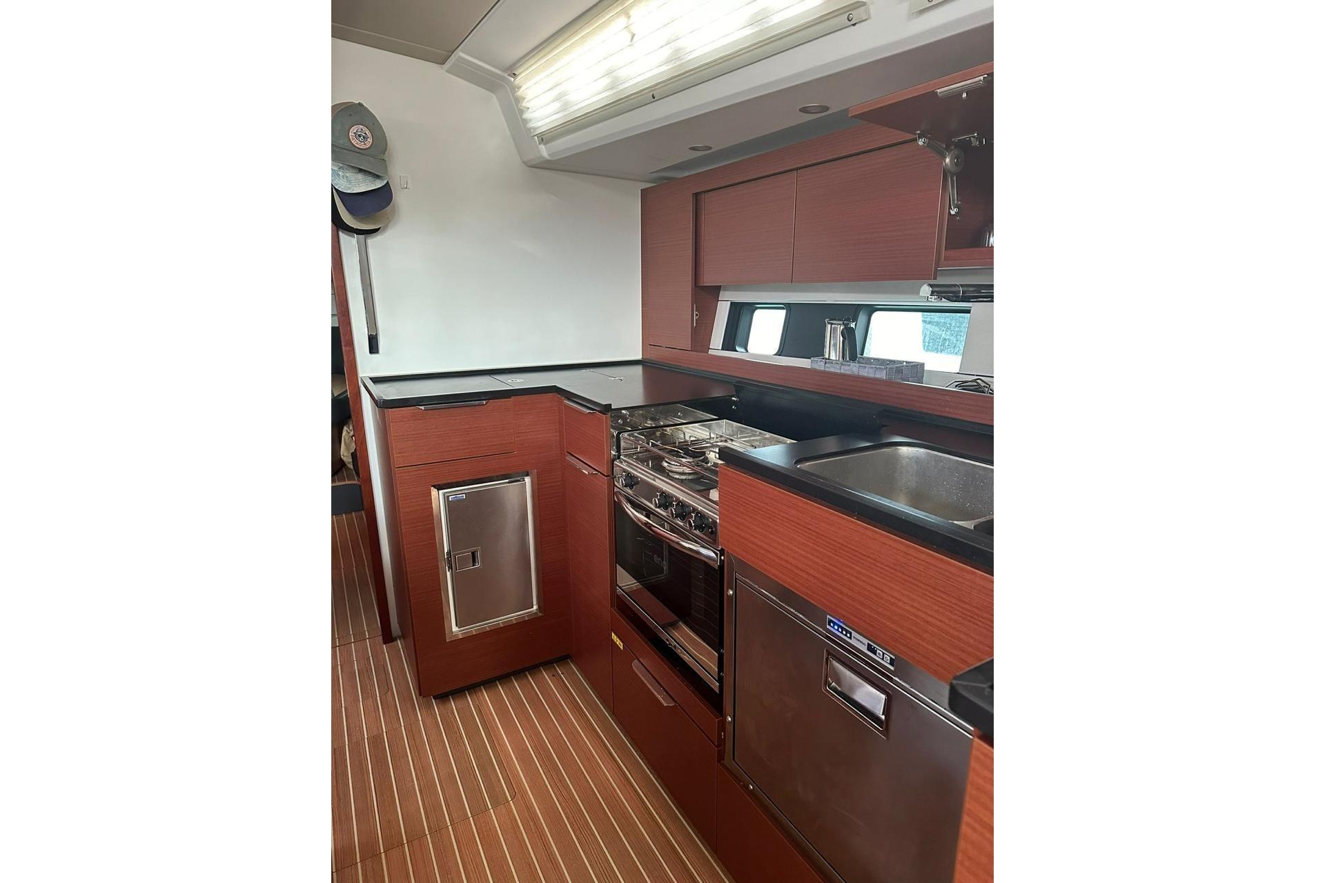 Modern kitchen interior of 2023 Hanse 460 yacht with wood cabinetry and stainless steel appliances.