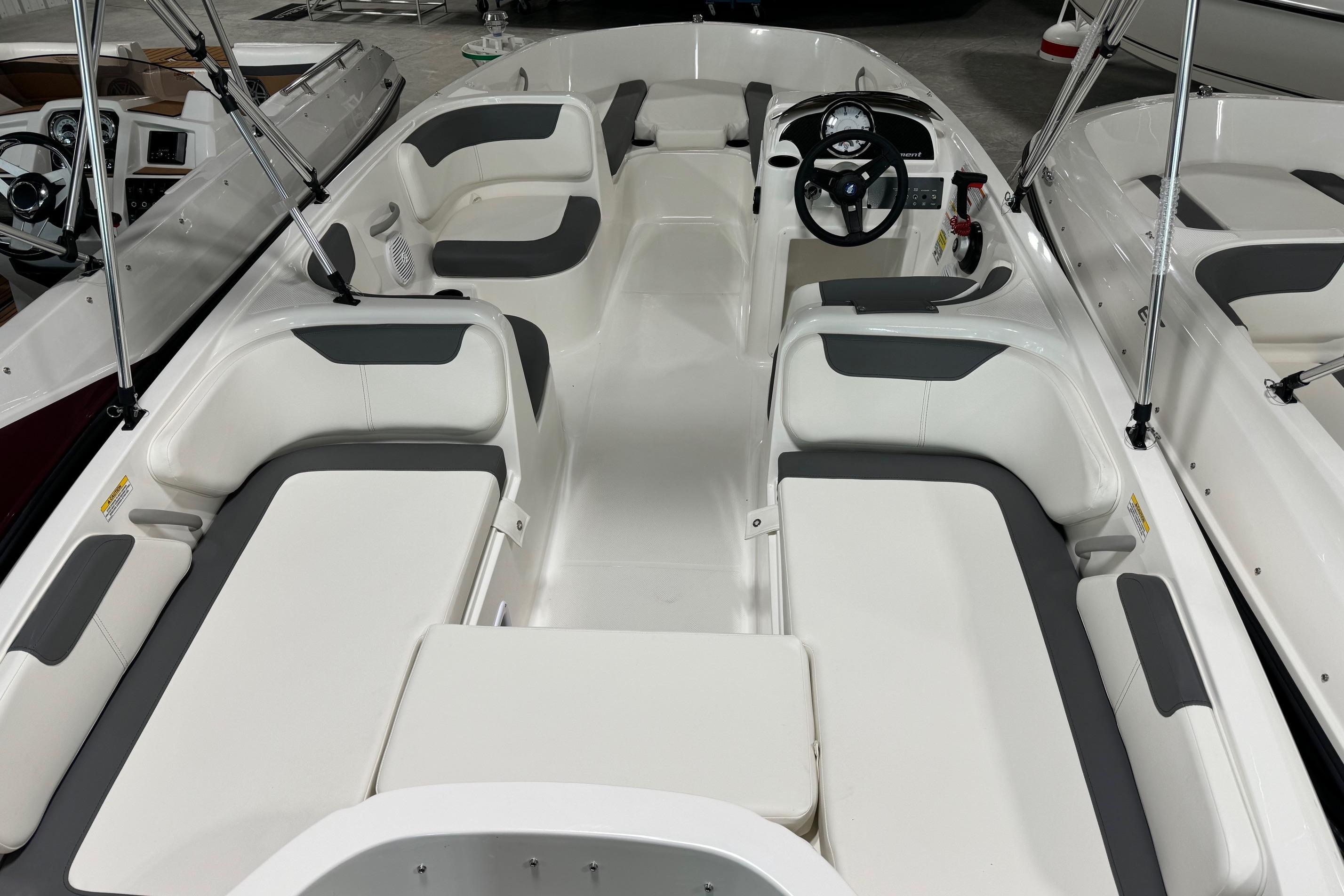 2025 Bayliner Element E18 boat interior with white and gray seating, steering wheel, and spacious layout.
