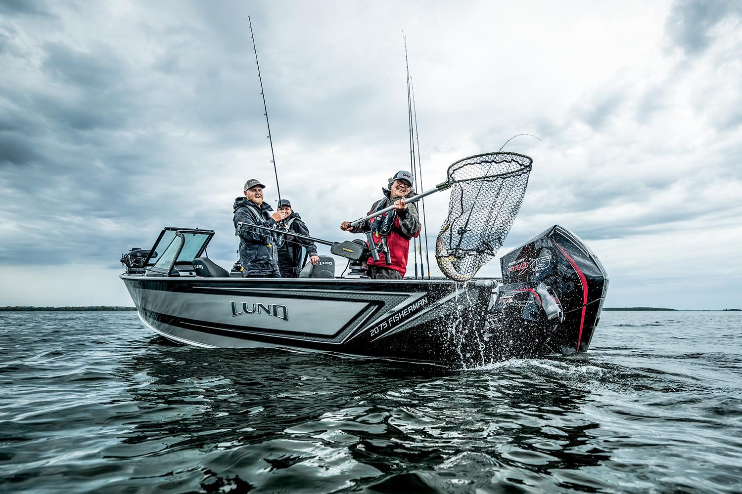 Manufacturer Provided Image: 2025 Lund 2075 Fisherman boat with anglers on a lake under cloudy skies.