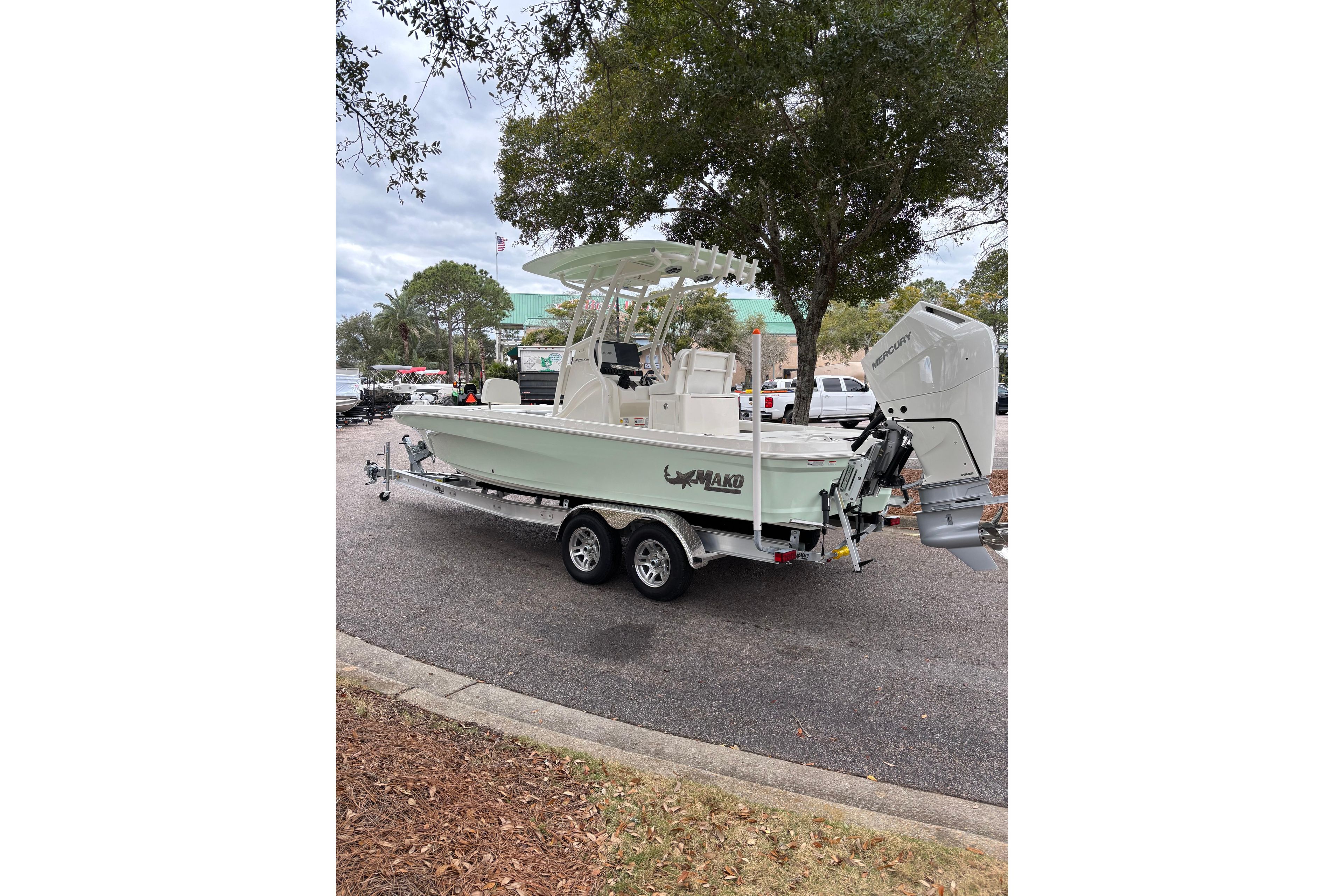 2026 Mako 24 APEX boat on trailer, parked outdoors near trees.
