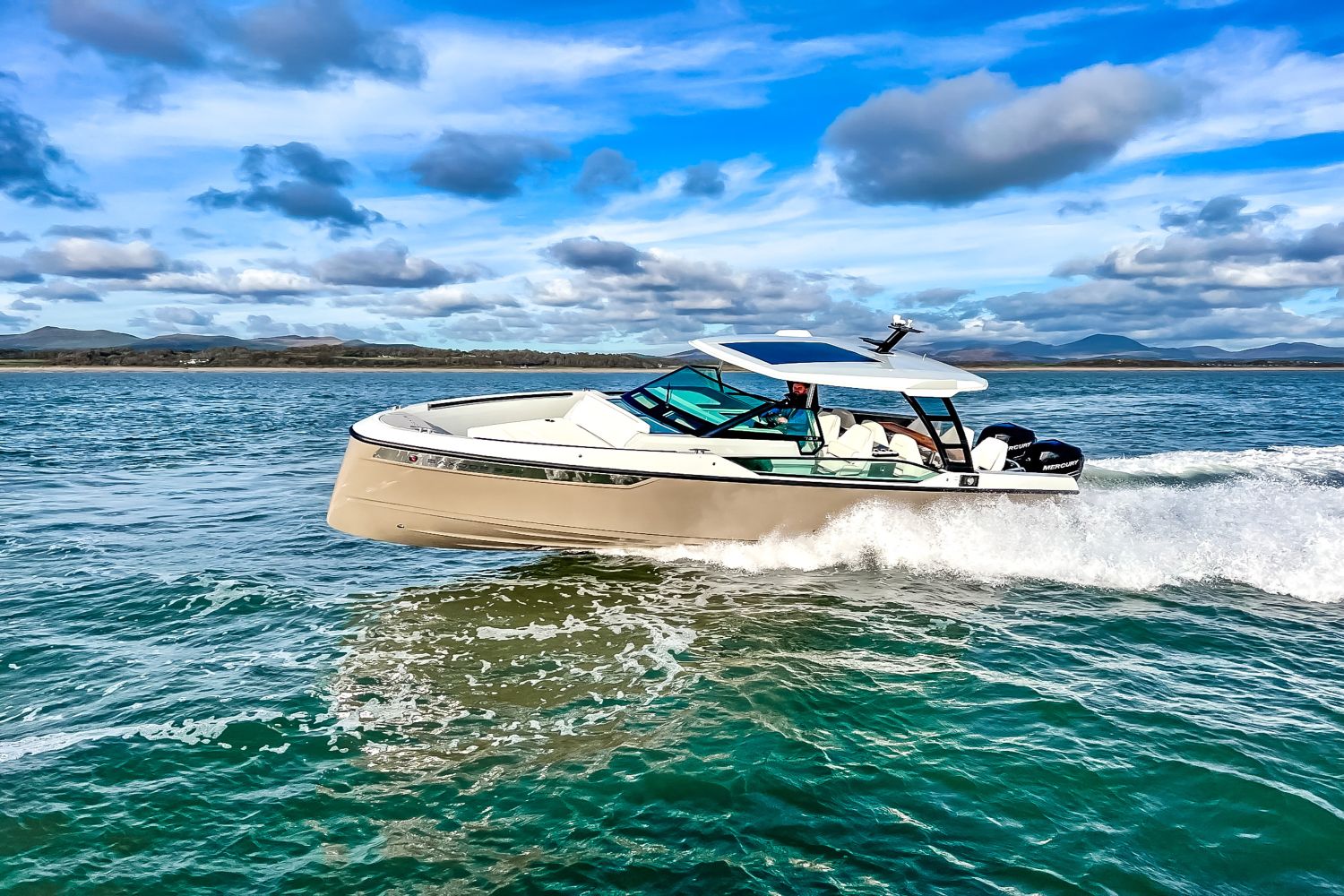 A 2027 Saxdor SX320 GTO cruising on the water with a scenic landscape in the background.