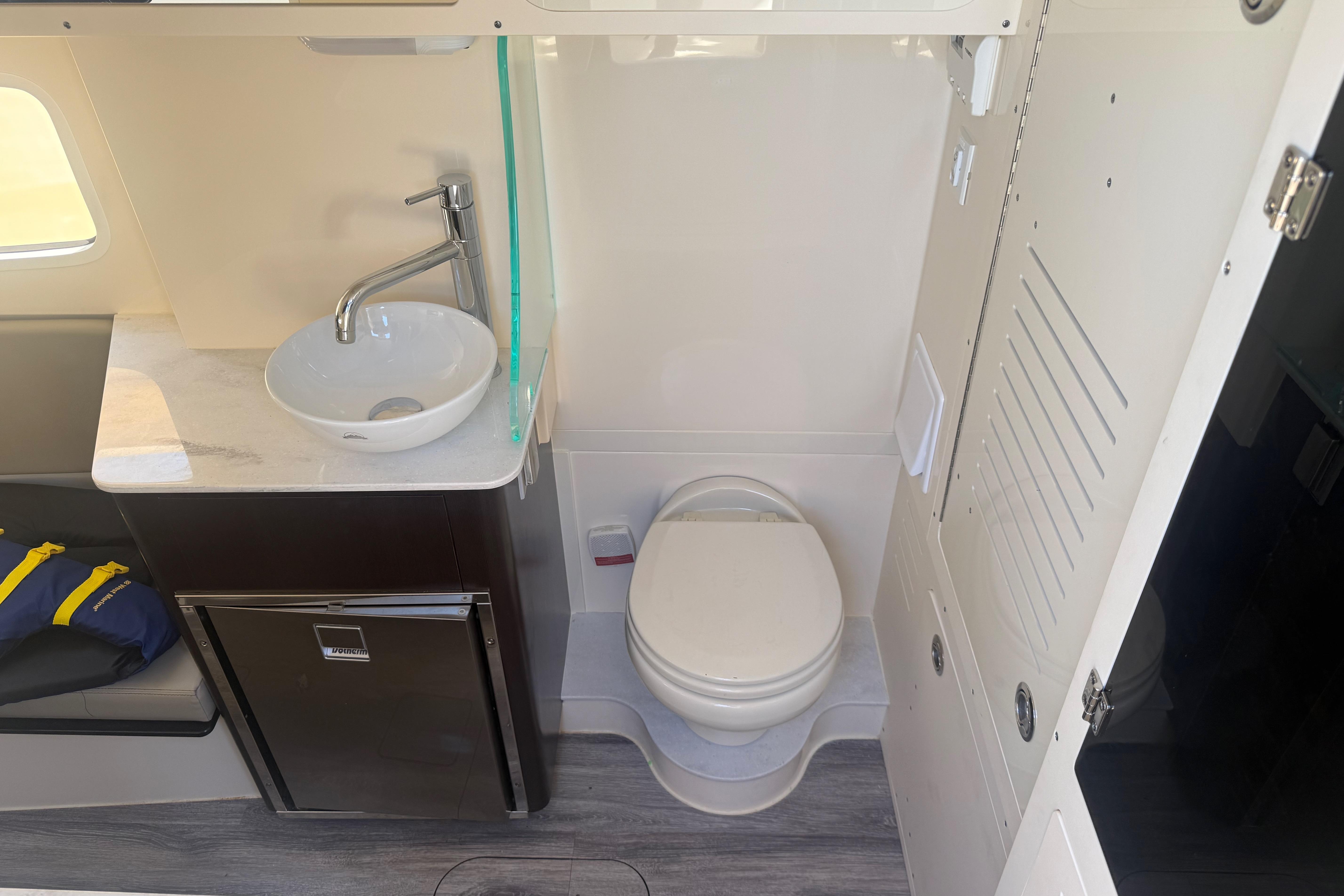 2022 Scout 355 LXF boat interior with sink, toilet, and storage cabinet.