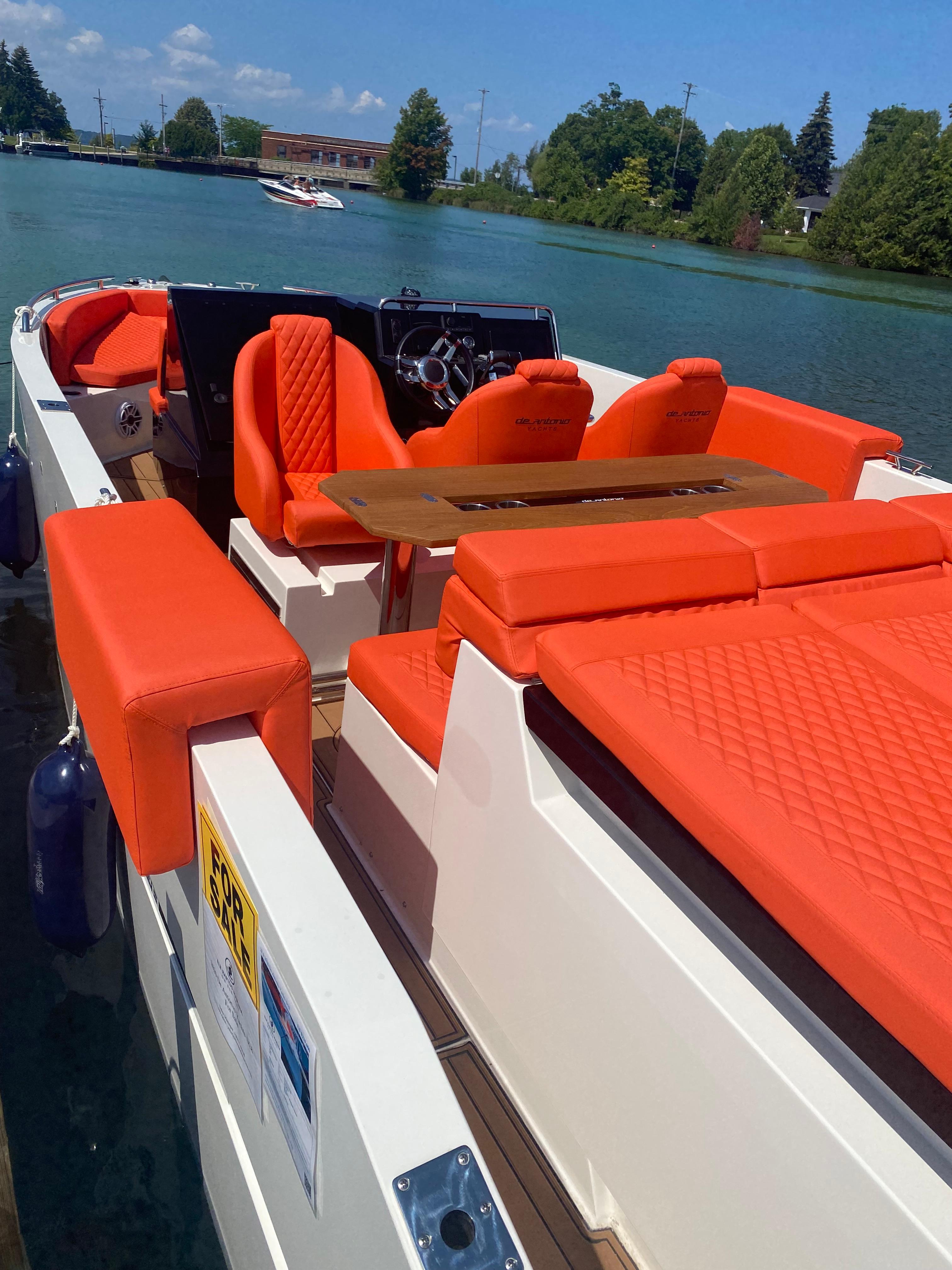 2020 De Antonio Yachts D 28 with vibrant orange seating on a serene lake.