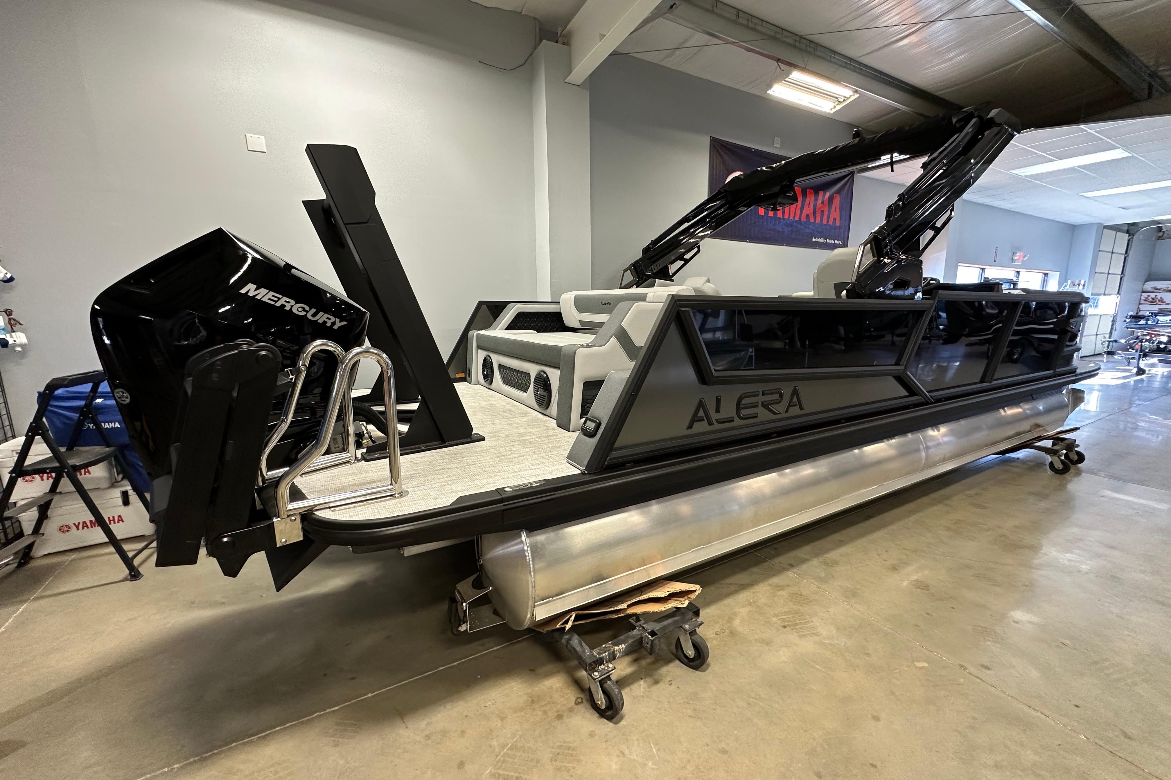 2026 Alera M25L pontoon boat with Mercury engine in showroom setting.