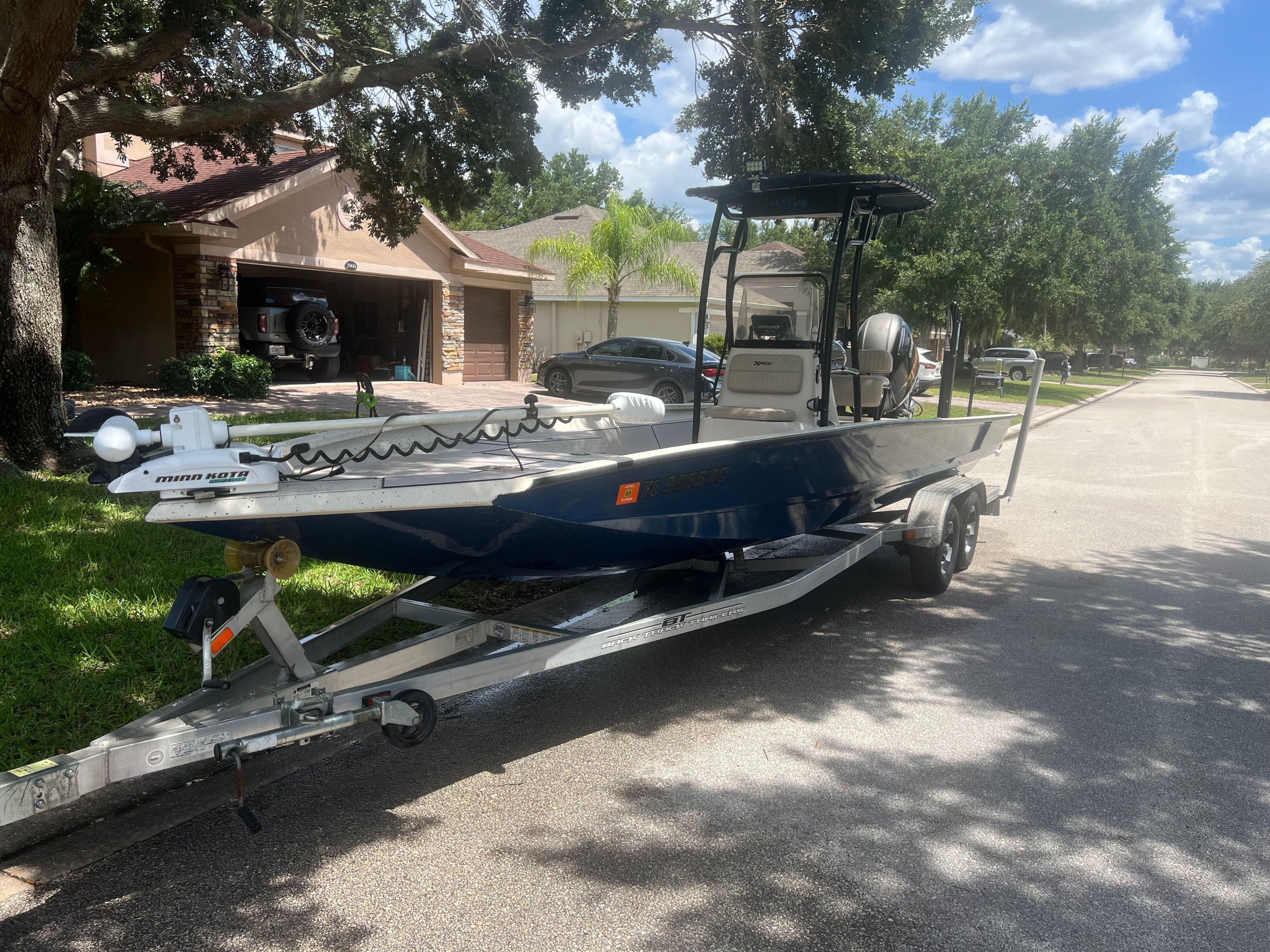 2016 Xpress H24B Bay boat on trailer in residential street.