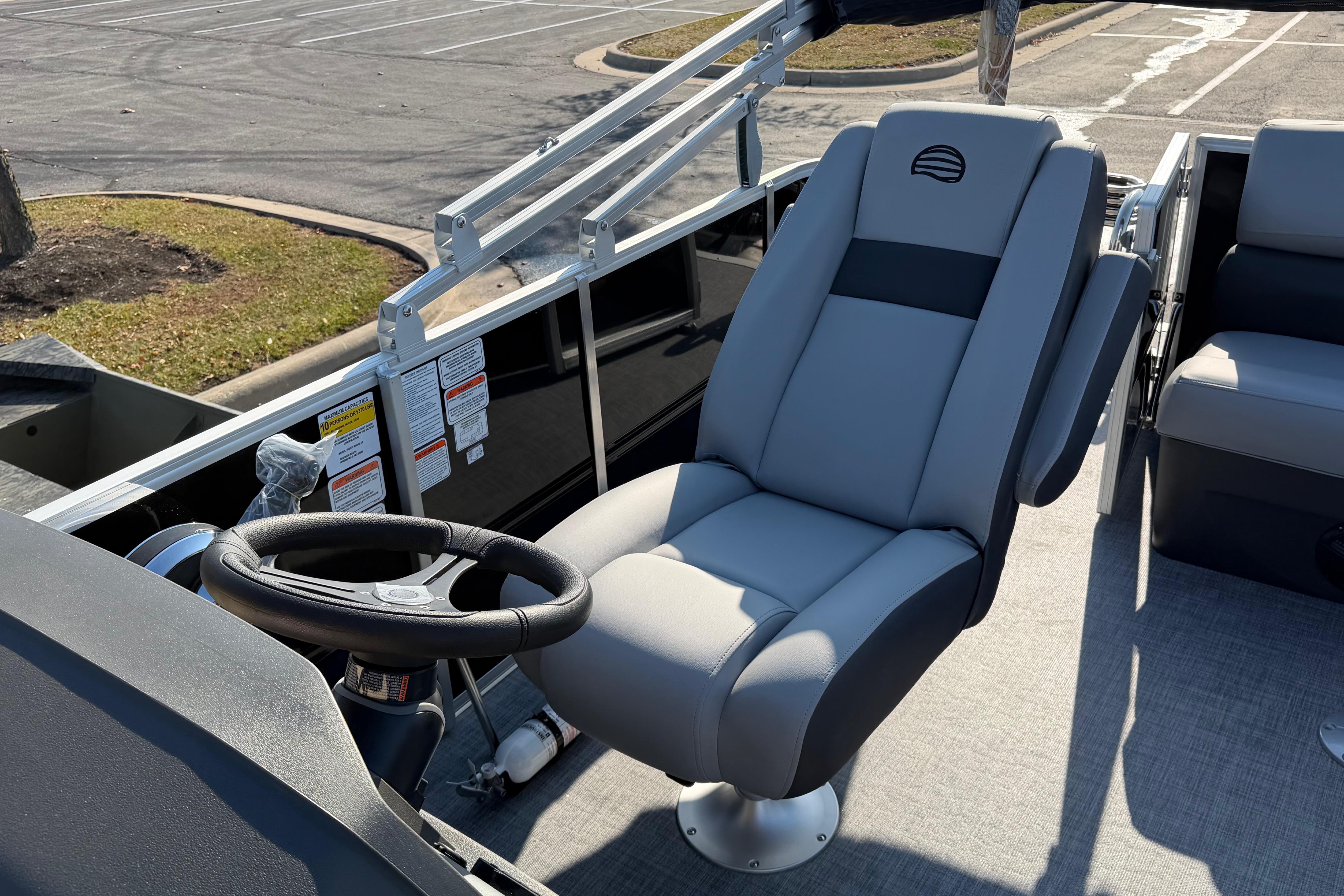 2026 Sun Tracker Party Barge 20 DLX helm seat and steering wheel in a parking lot.