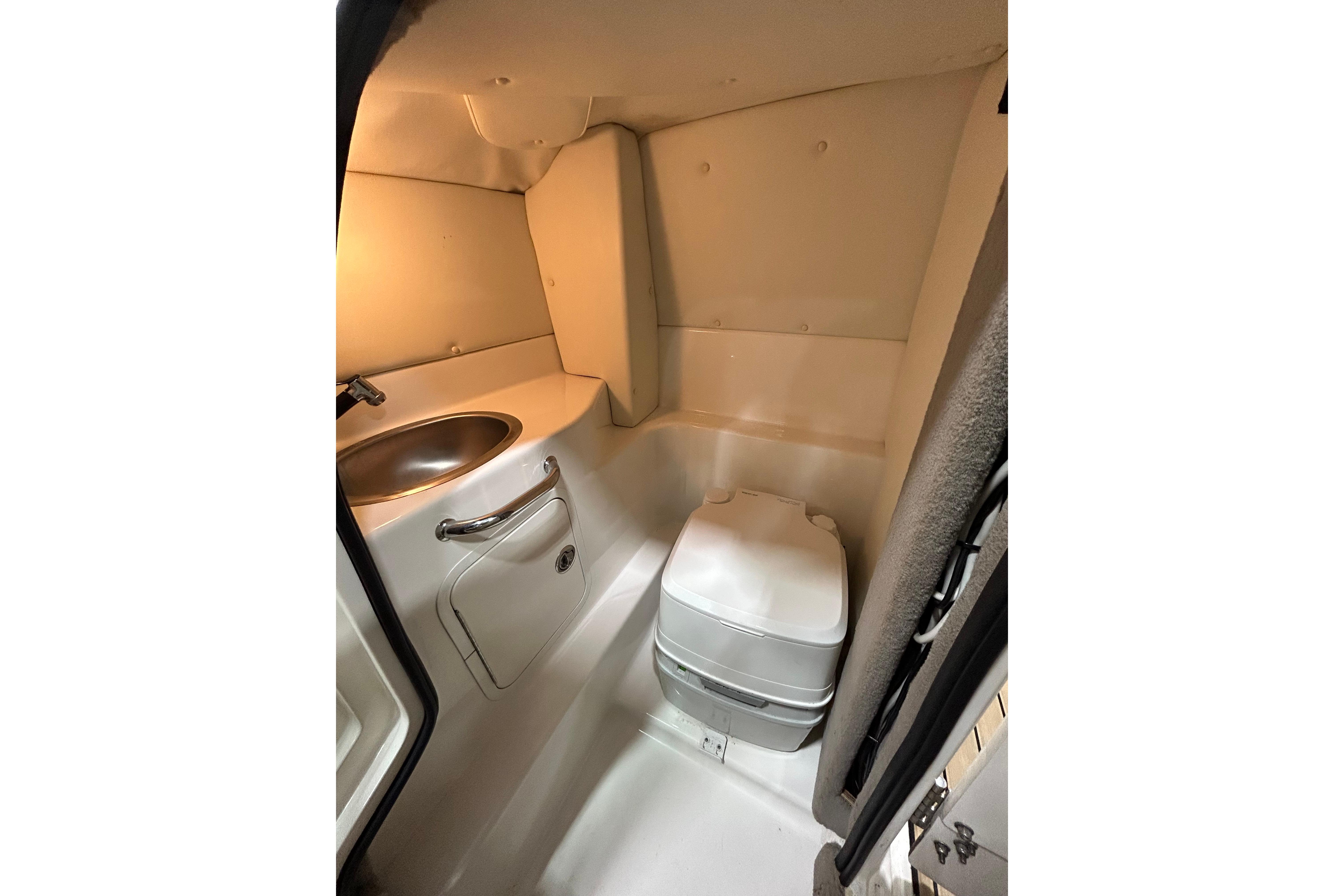 Compact bathroom in 2006 Sea Ray 270 SLX boat, featuring a sink and portable toilet.