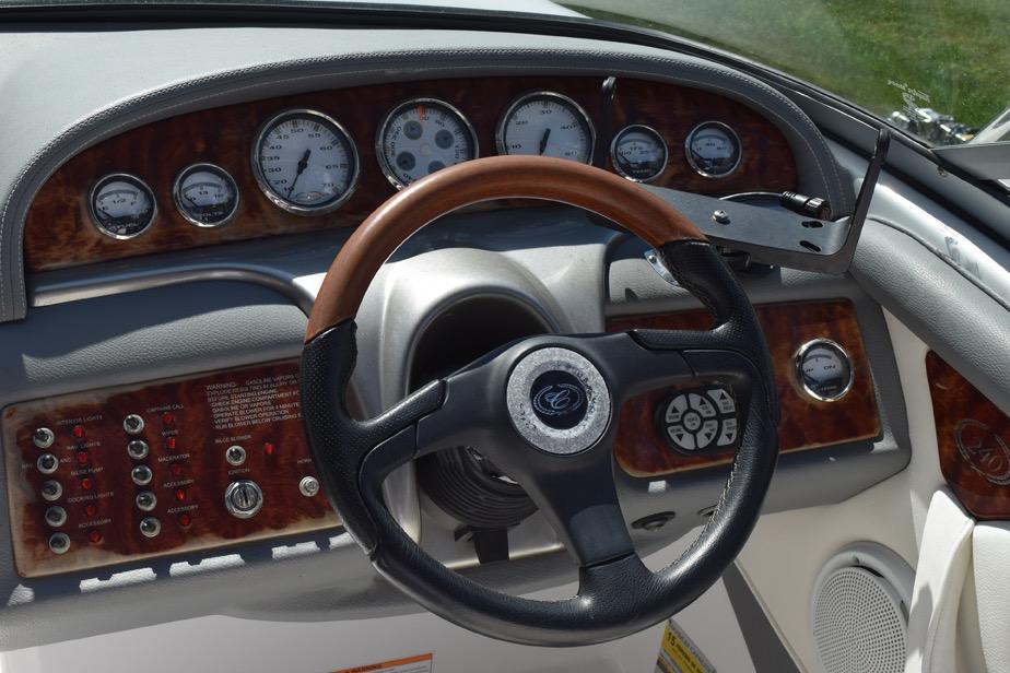 Steering wheel and dashboard of a 2006 Cobalt 240 boat with wood accents and gauges.
