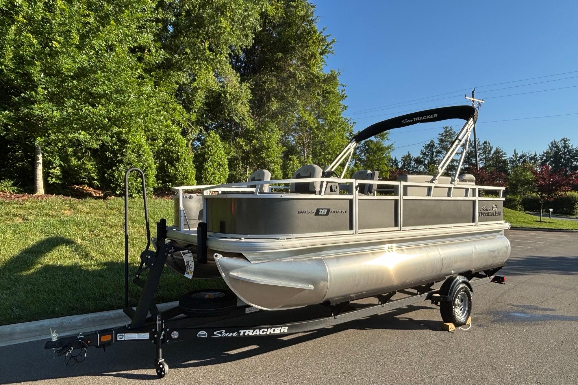 2026 Sun Tracker Bass Buggy 18 DLX pontoon boat on trailer, parked outdoors.