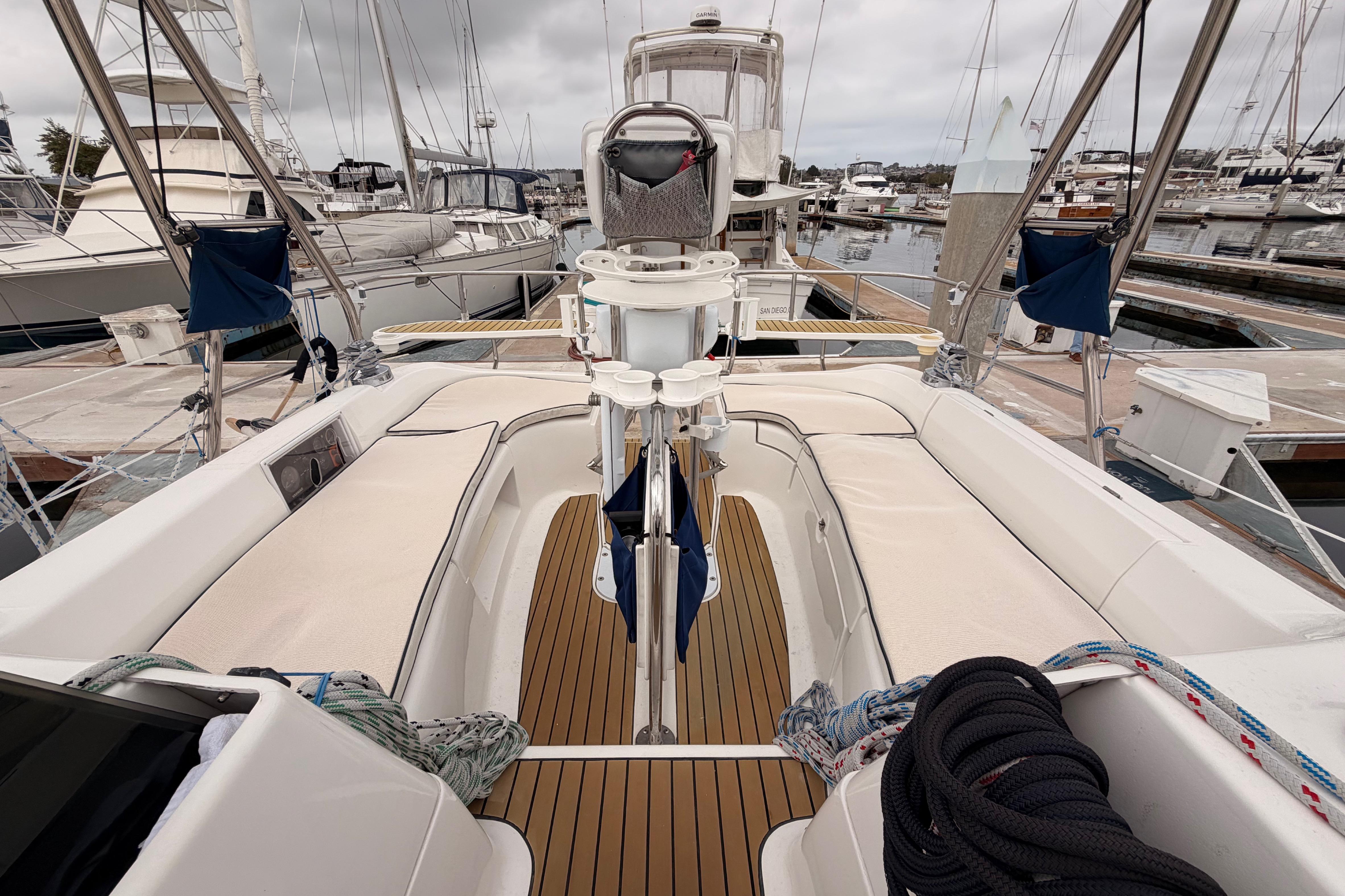 2009 Hunter 38 sailboat with teak deck, docked in a marina under cloudy skies.