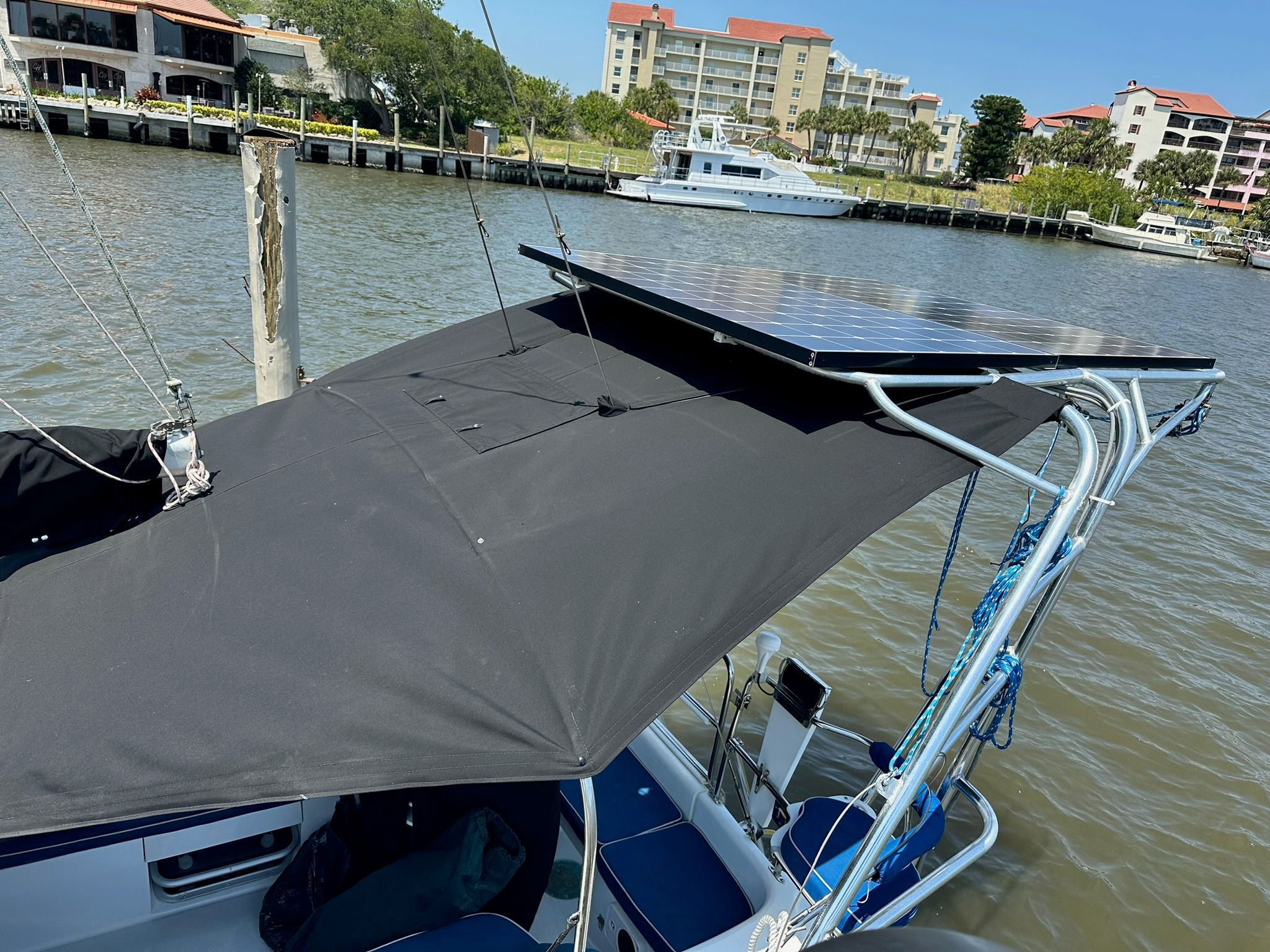 A Catalina MkII boat with solar panels on the roof, docked in a marina.