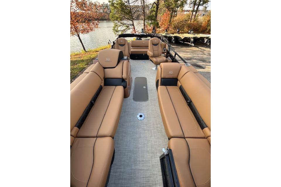 2025 Regency 230 LE3 Sport boat interior with tan leather seating, docked by a scenic lake.