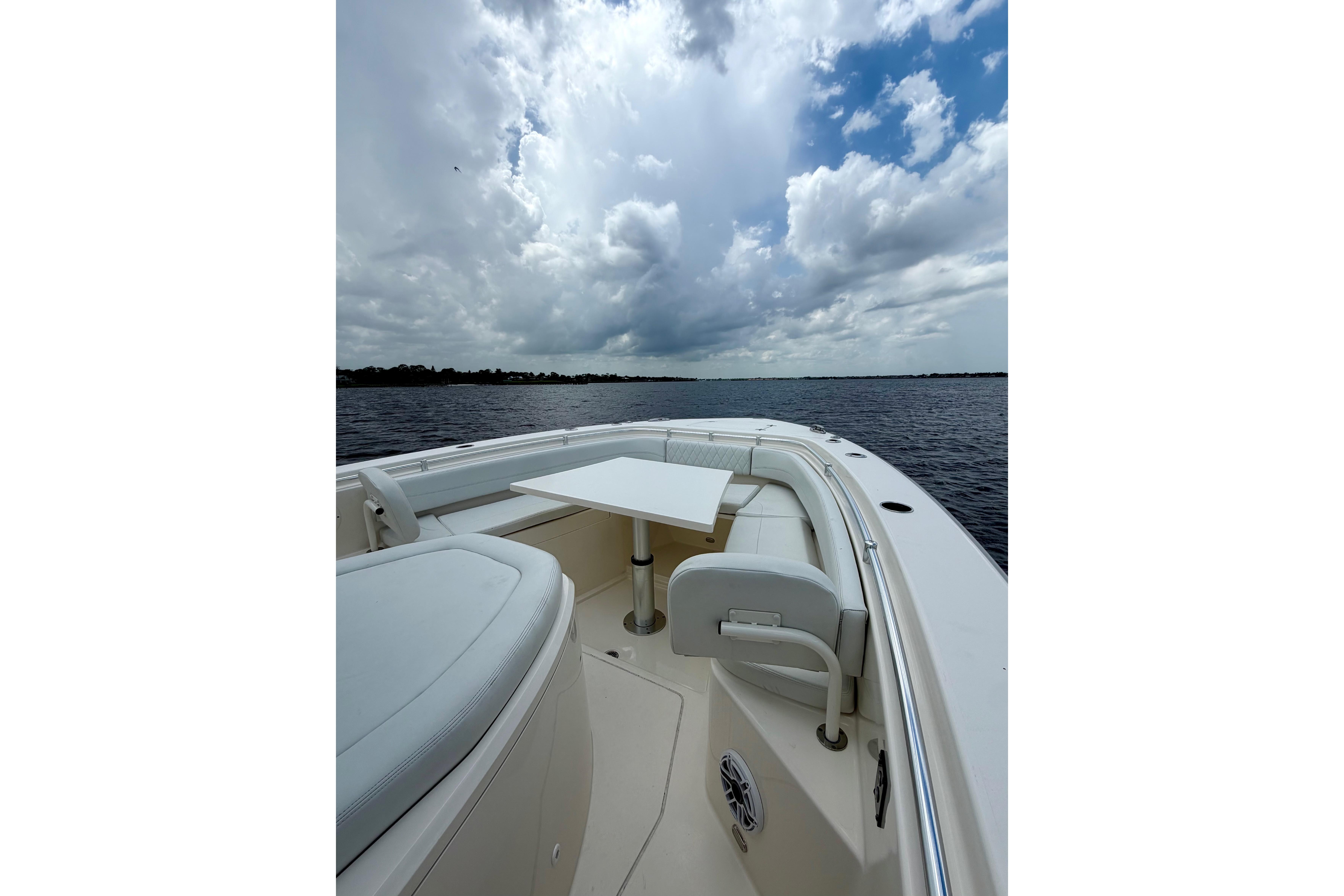 2023 Cobia 350 Center Console boat interior with table, under cloudy sky on water.