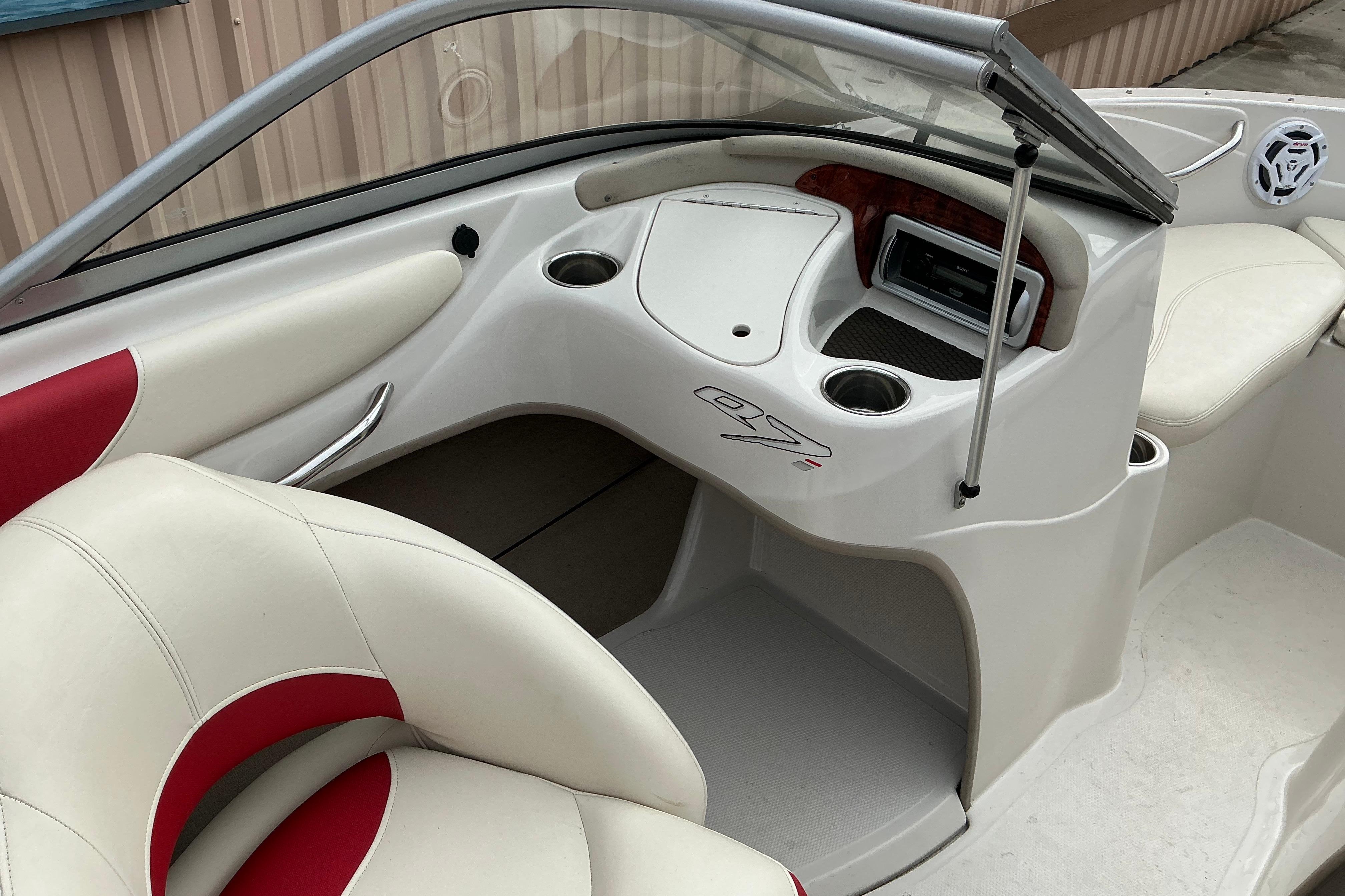 Interior of a 2014 Tahoe Q7i boat featuring white and red seating and dashboard controls.