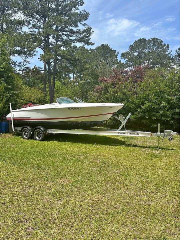 2001 Chris-Craft Launch 22 boat on trailer in grassy area with trees.