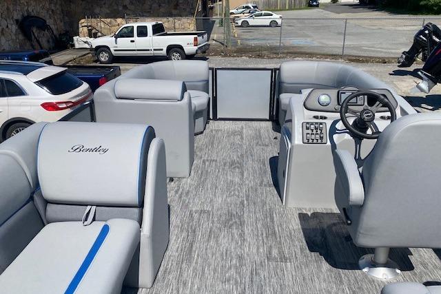 The image shows the interior of a Bentley Pontoons boat with gray seating and a helm station.