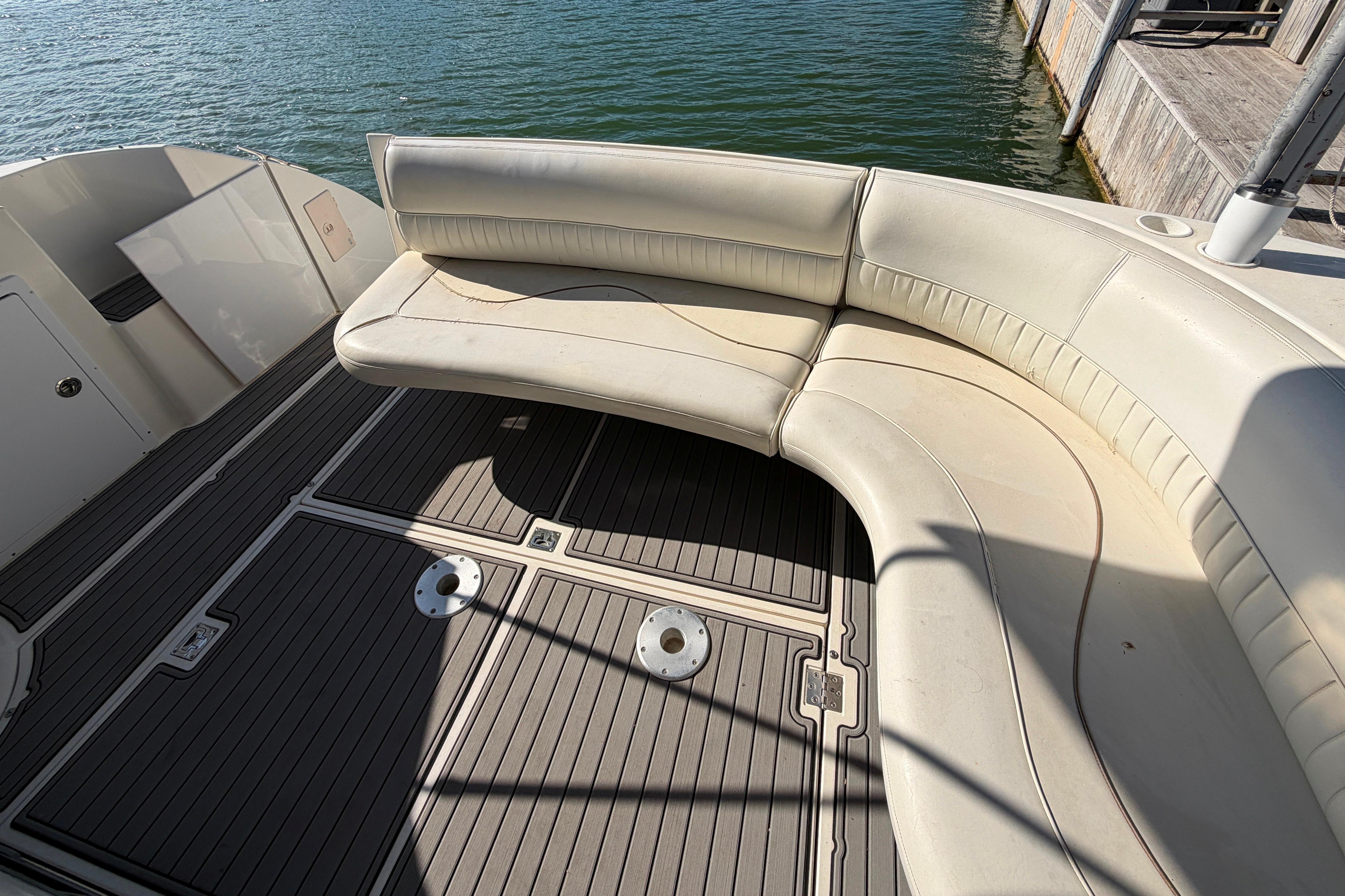 1997 Cruisers 3575 boat with curved seating and teak deck by the water.
