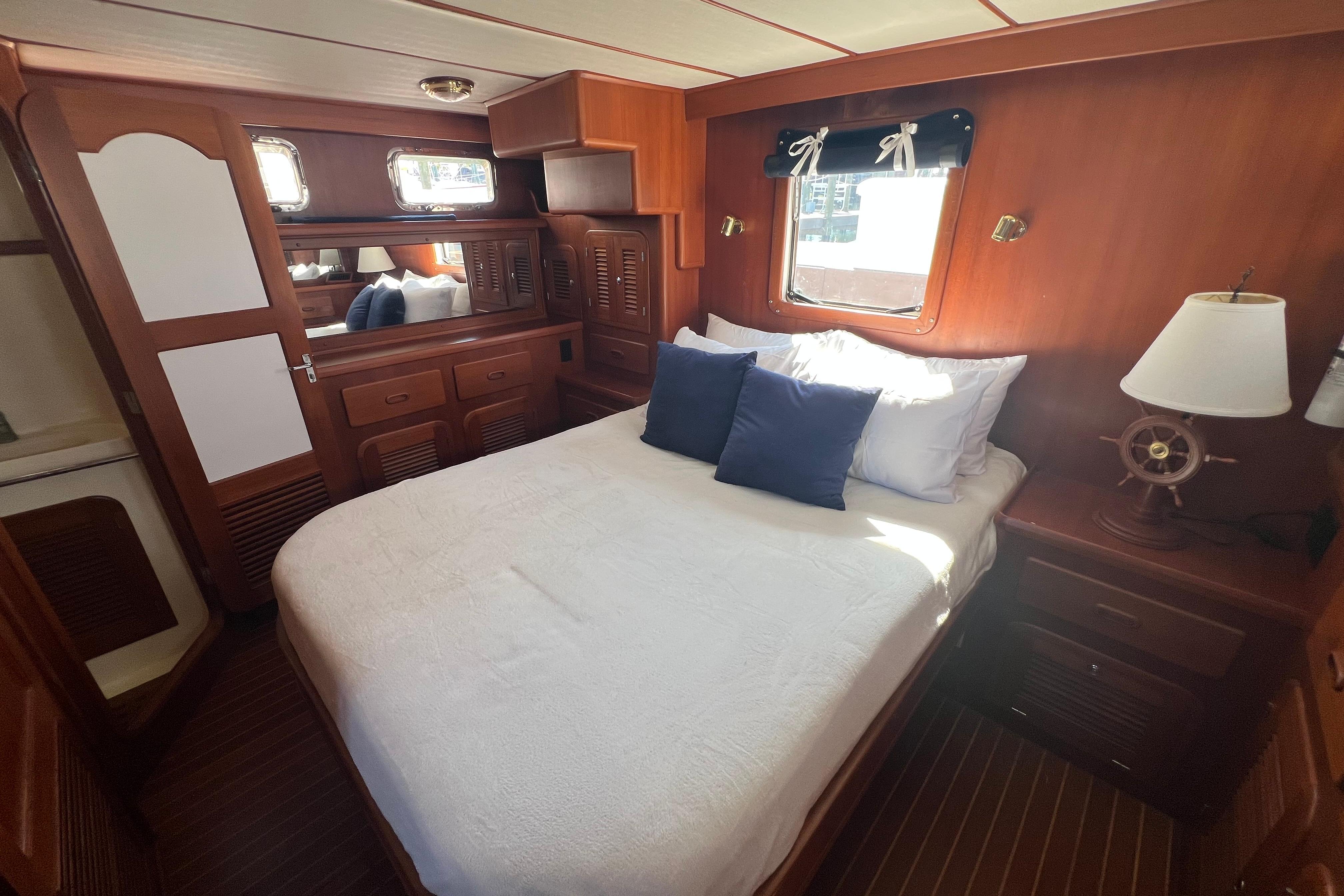 Cozy bedroom in 2007 Heritage East 36 Sundeck Trawler with wooden interior and nautical decor.