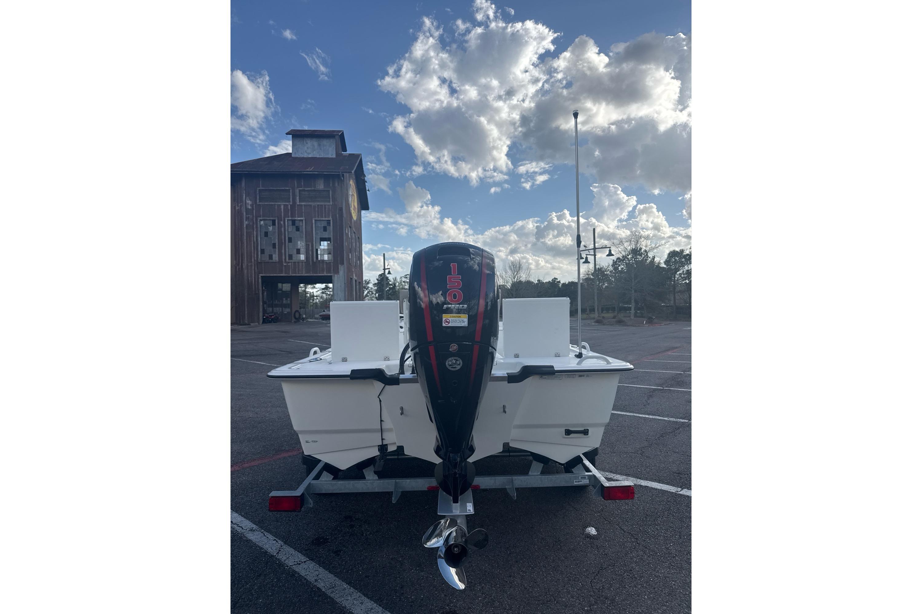 2026 Mako Pro Skiff 19 CC boat with outboard motor in parking lot under cloudy sky.