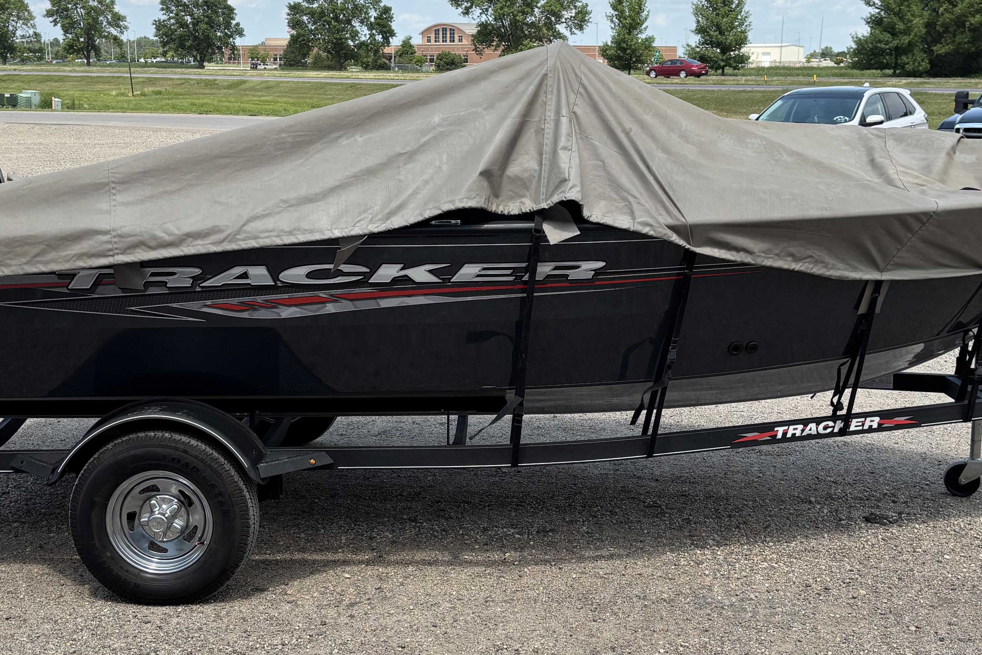 2021 Tracker Pro Guide V-16 WT boat covered on a trailer in a parking lot.