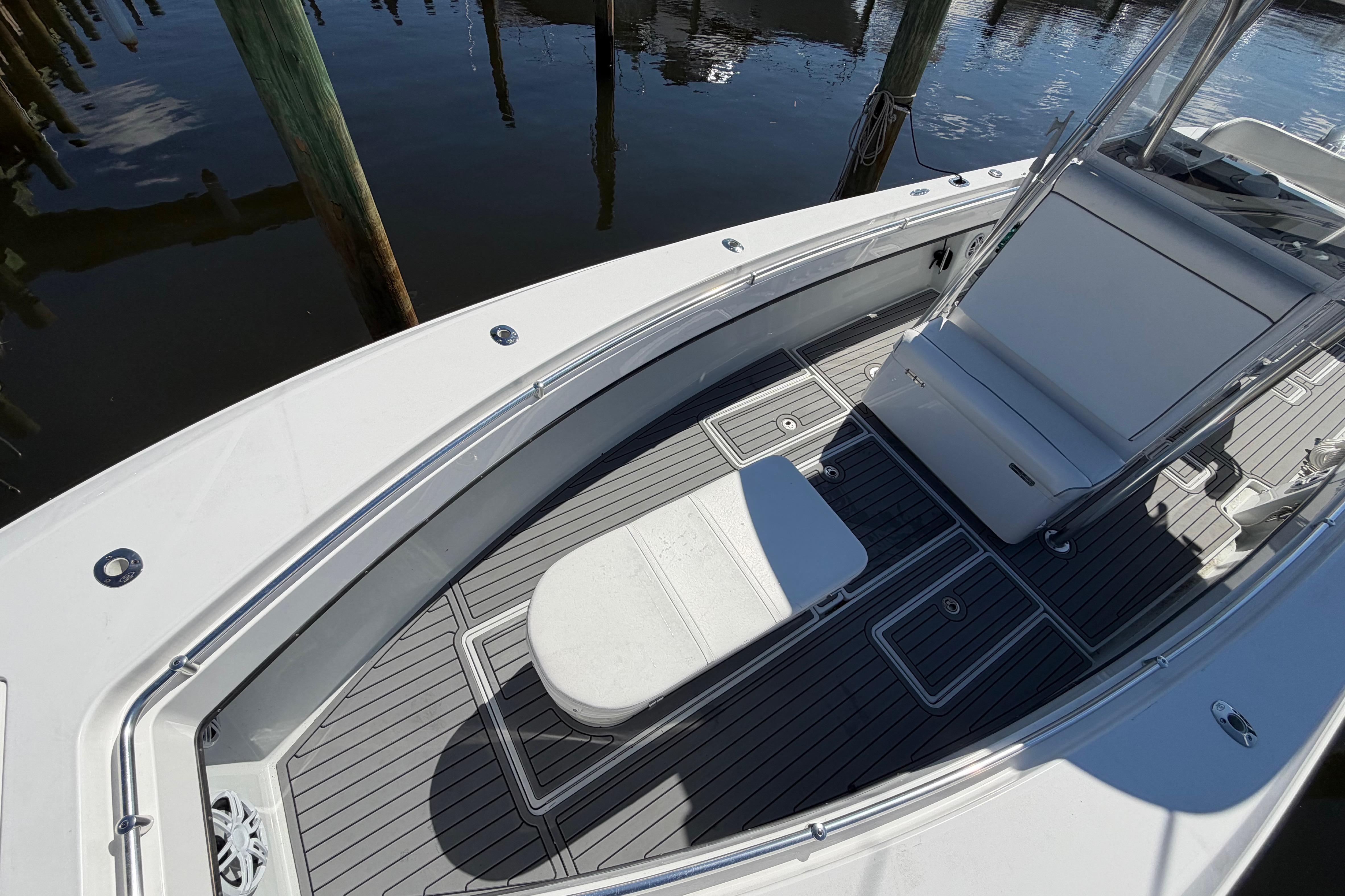 2015 Contender 32 ST boat deck with seating, docked by wooden posts.
