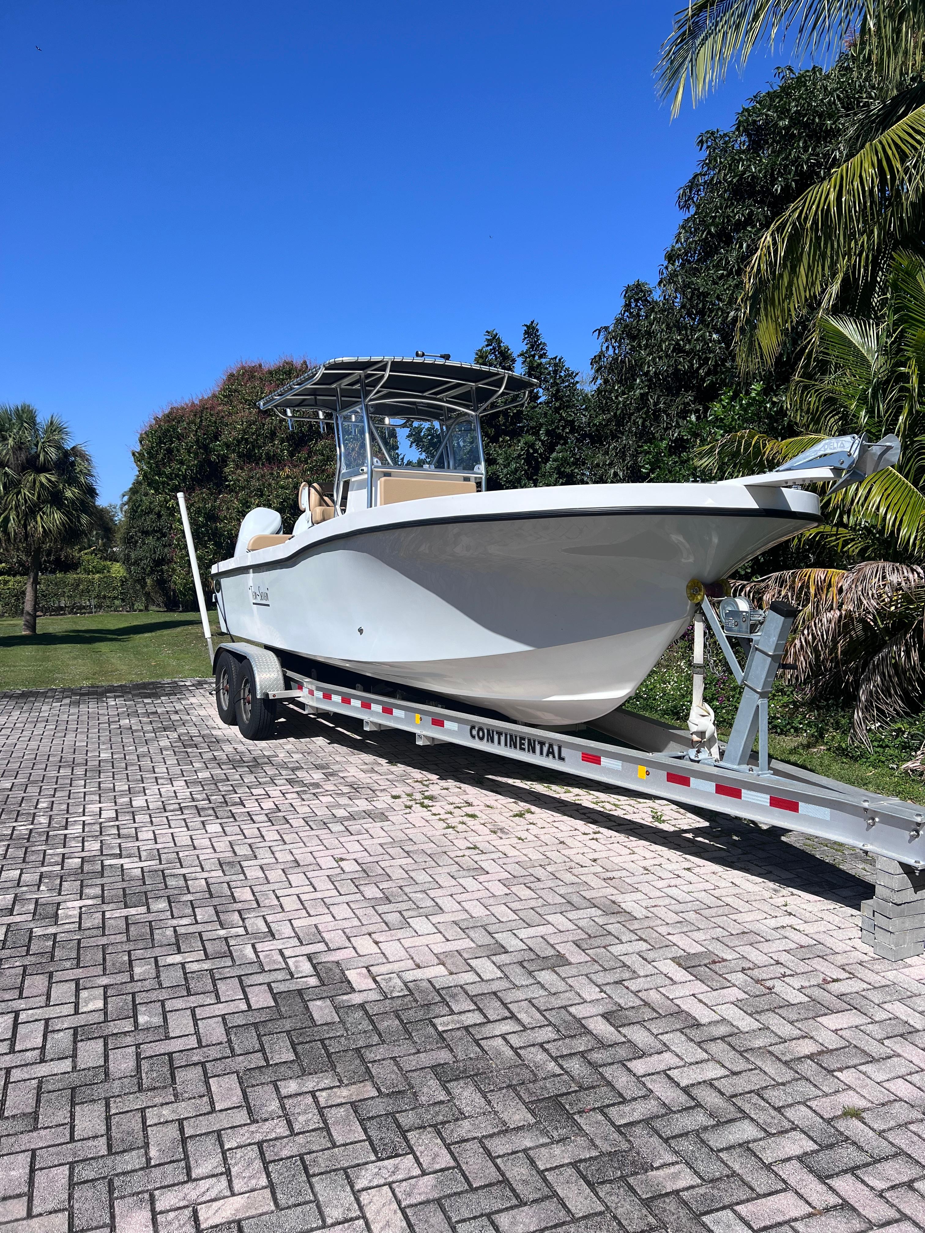 2022 Dusky 278 Center Console boat on a trailer in a tropical setting.