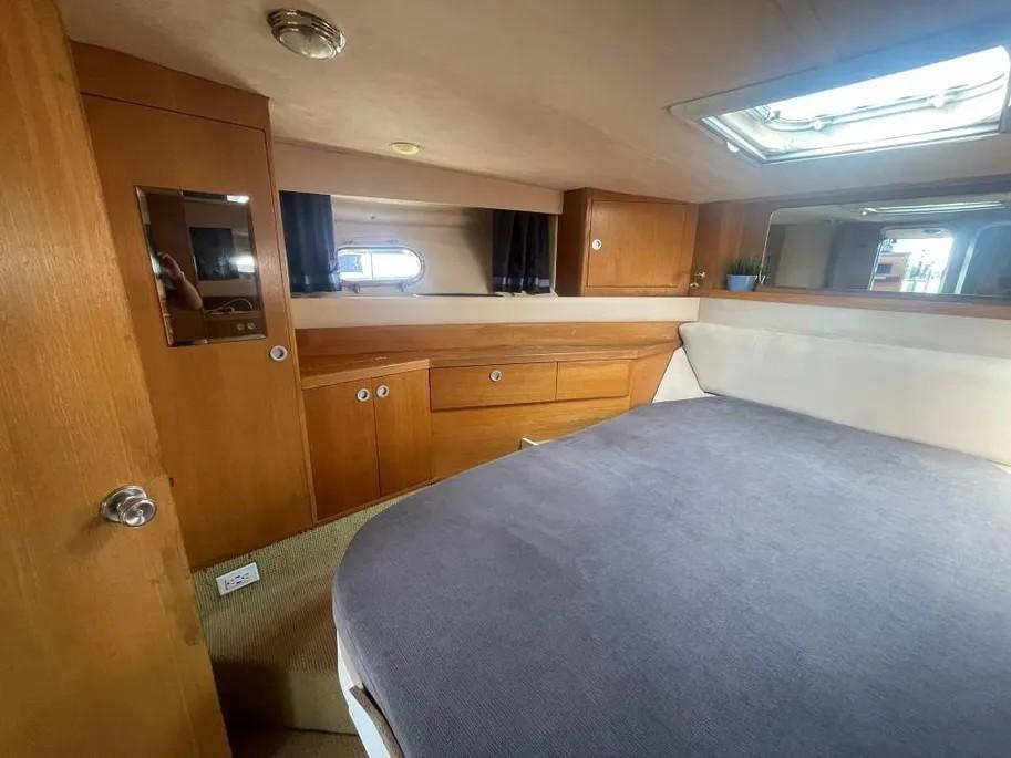 Interior of 1985 Princess Sedan Flybridge, featuring cozy cabin with bed and wooden cabinetry.
