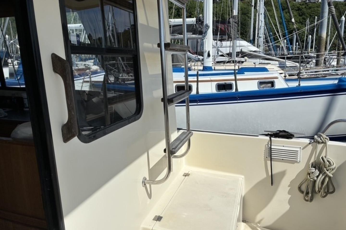Nordic Tug 37 boat deck, 2000 model, with docked sailboats in the background.