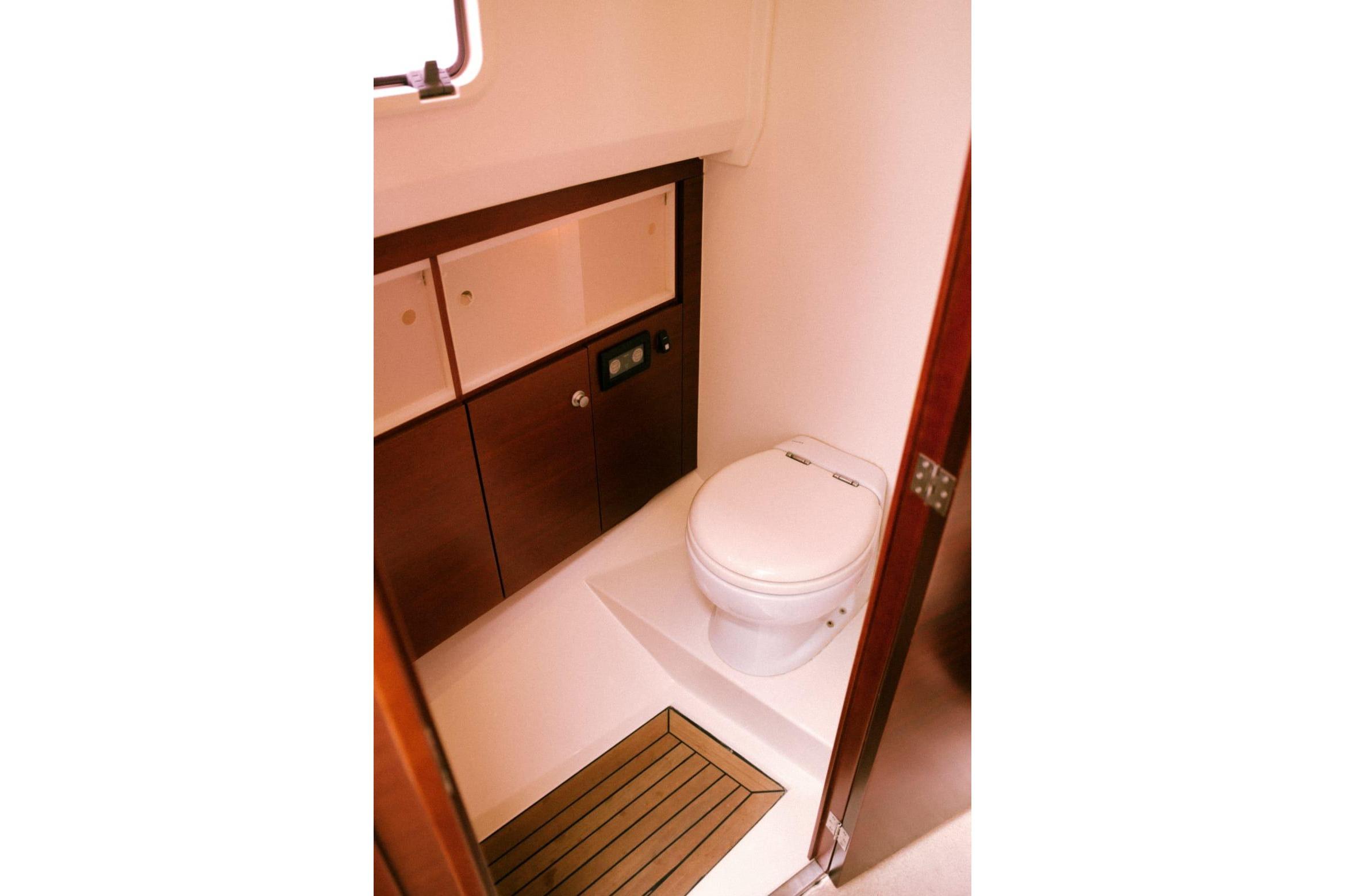 Compact bathroom in 2008 Fjord 40 Open yacht with wooden cabinetry and toilet.