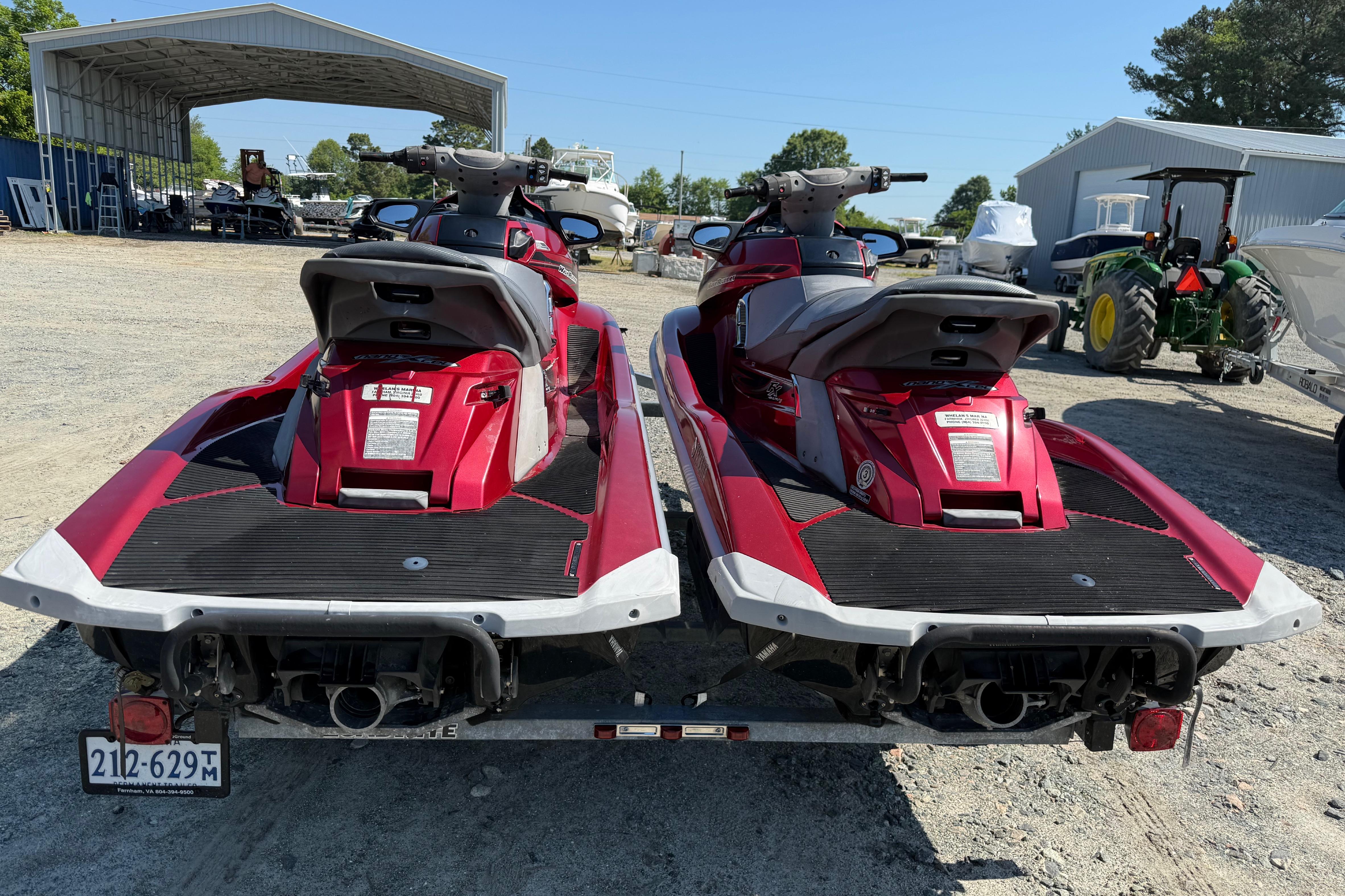 Two red 2013 Yamaha WaveRunner FX HO jet skis on a trailer in a yard.