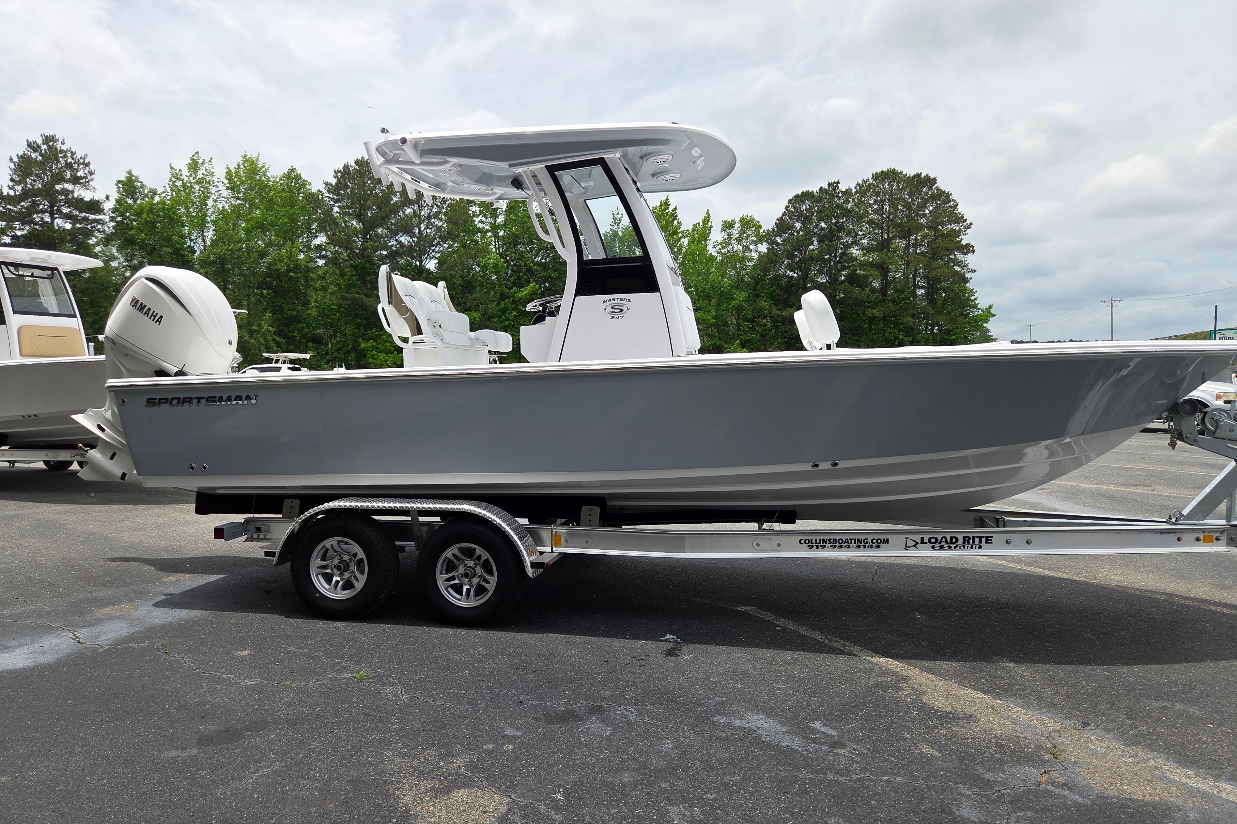 2026 Sportsman Masters 247 Bay Boat on trailer, parked outdoors with trees in background.