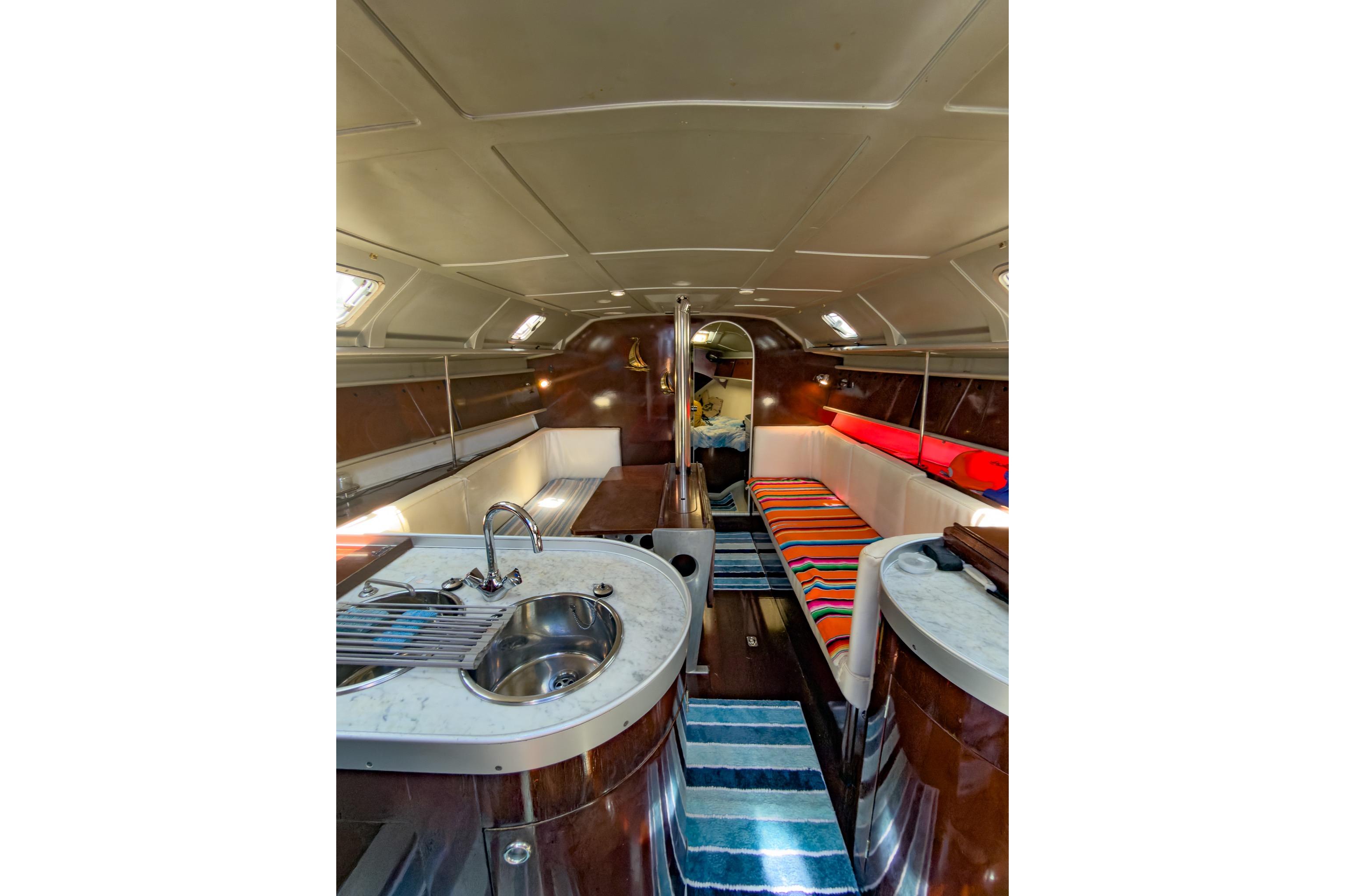 Interior of 1993 Beneteau First 38 s5 yacht, featuring cozy seating and compact kitchen area.