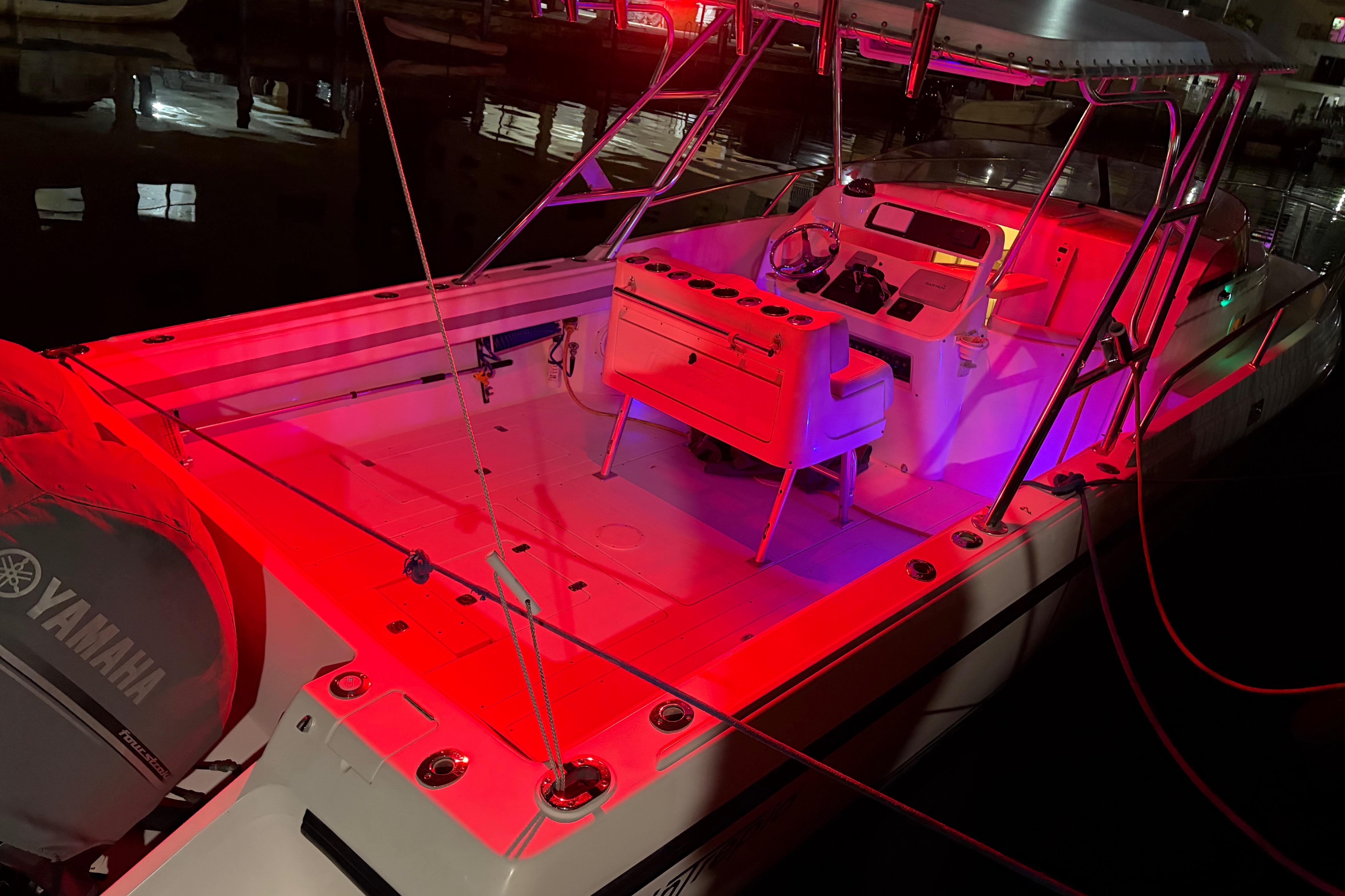 1998 Intrepid 339 Walkaround boat illuminated with vibrant red and purple lights at night.