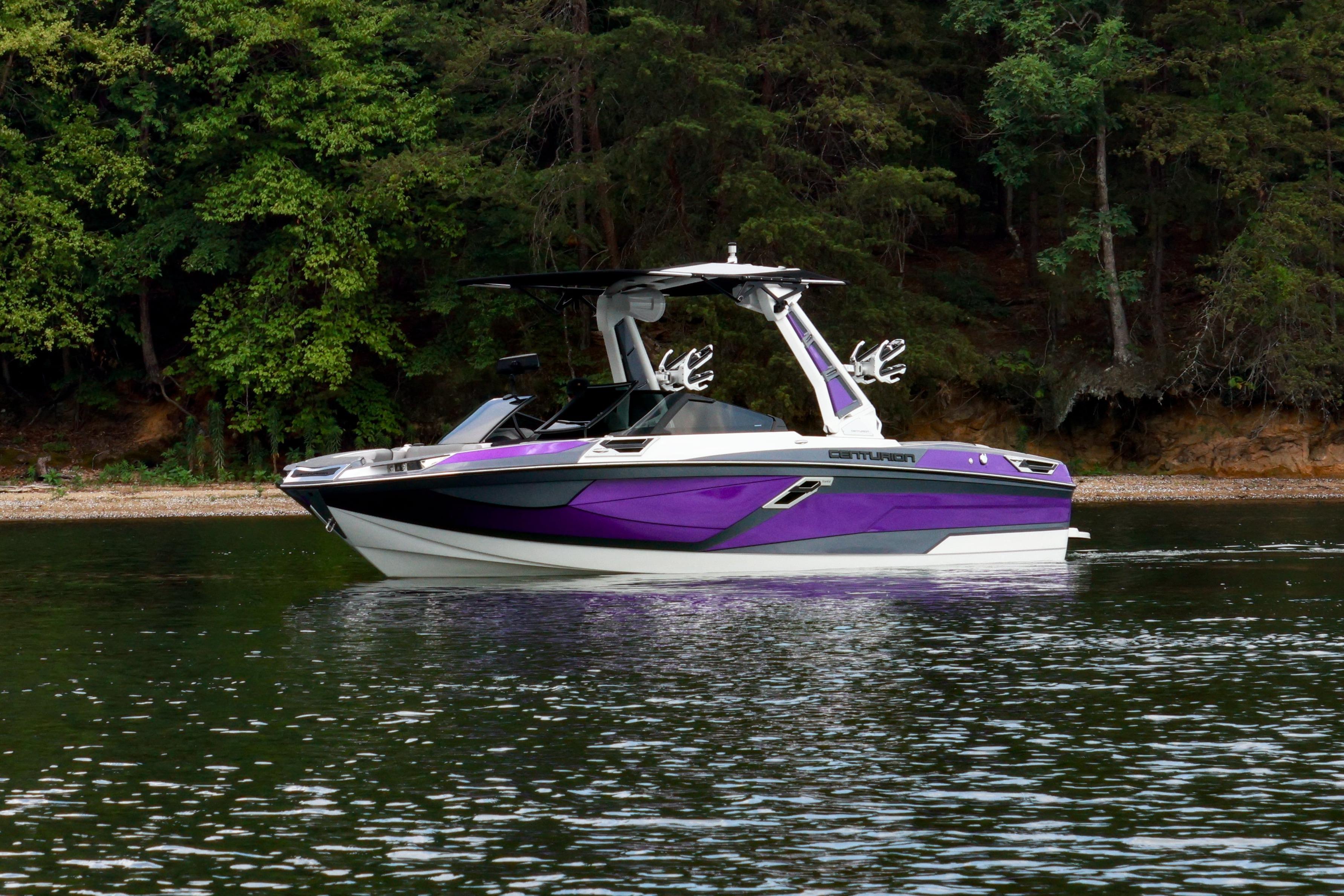 2022 Centurion Ri245 boat with purple accents on a calm lake near a forested shoreline.